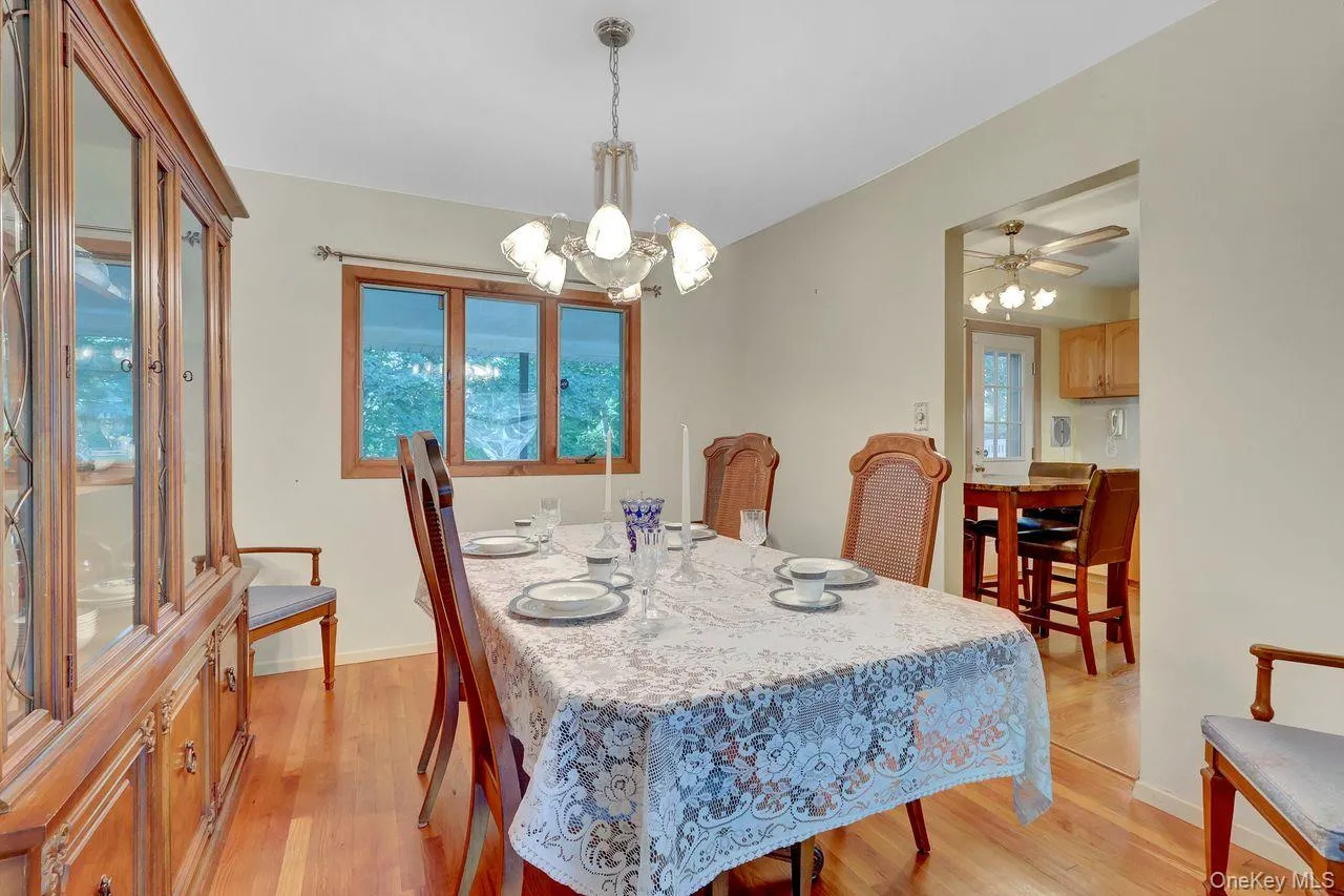 Hardwood flooring throughout, a multi-pane window with wood trim, and a chandelier lighting fixture Hardwood flooring throughout, a multi-pane window with wood trim, and a chandelier lighting fixture