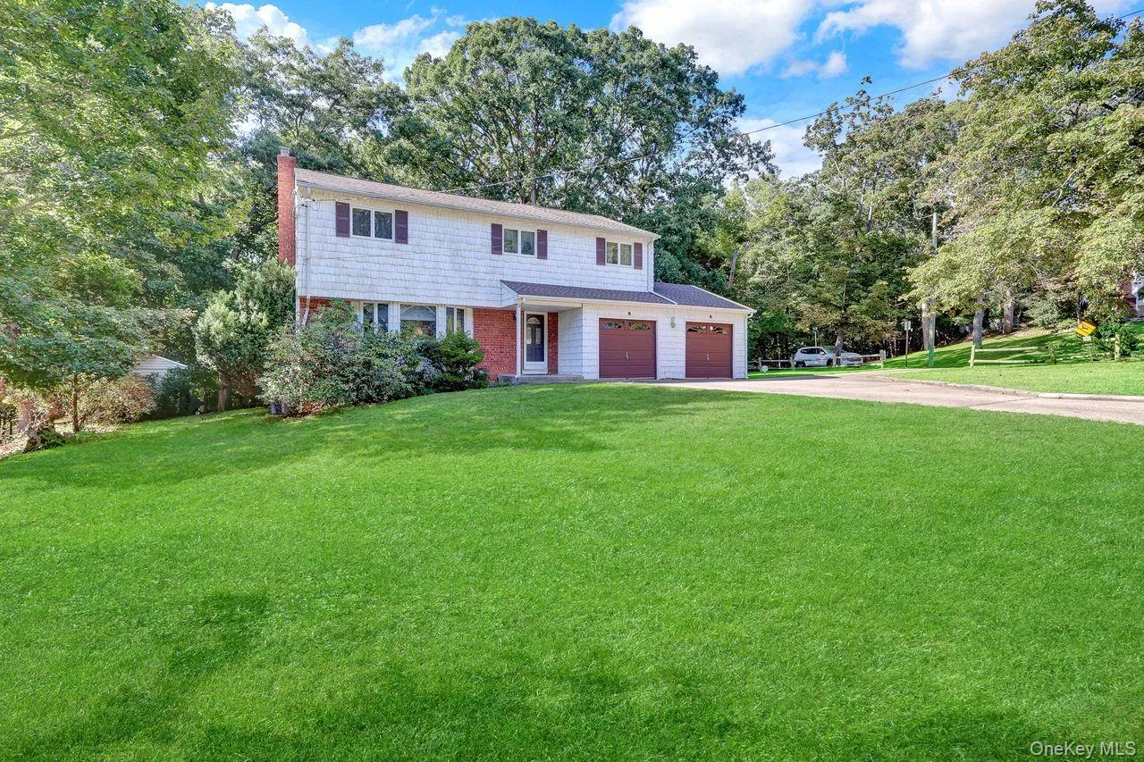 Two-story Colonial with white shake siding and brick accents, featuring a two-car garage duel driveway, on a corner lot. Two-story Colonial with white shake siding and brick accents, featuring a two-car garage duel driveway, on a corner lot.