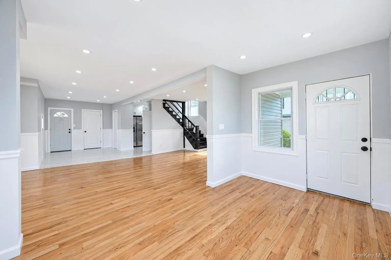 Hardwood flooring, recessed lighting, wainscoting, white interior doors, and a staircase with dark risers Hardwood flooring, recessed lighting, wainscoting, white interior doors, and a staircase with dark risers