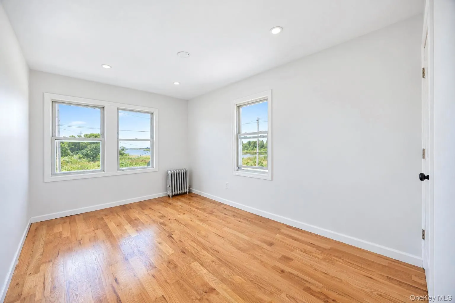 Hardwood flooring, recessed lighting, multiple windows, and a panel radiator Hardwood flooring, recessed lighting, multiple windows, and a panel radiator