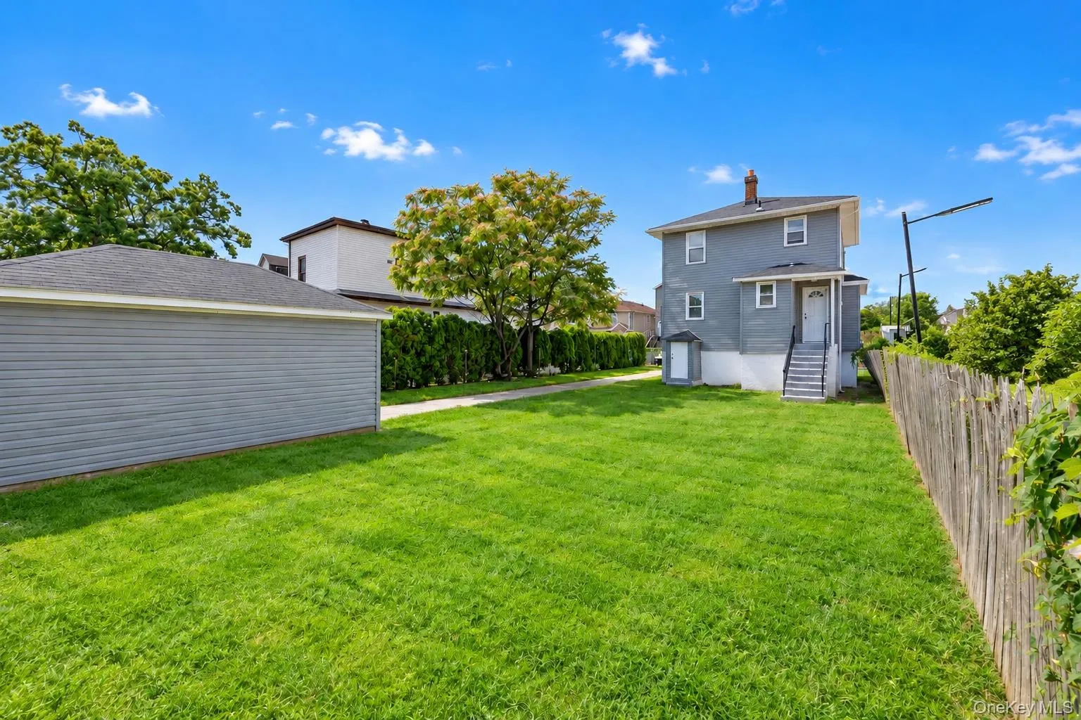 Expansive lawn with a detached garage featuring siding and a shingle roof Expansive lawn with a detached garage featuring siding and a shingle roof