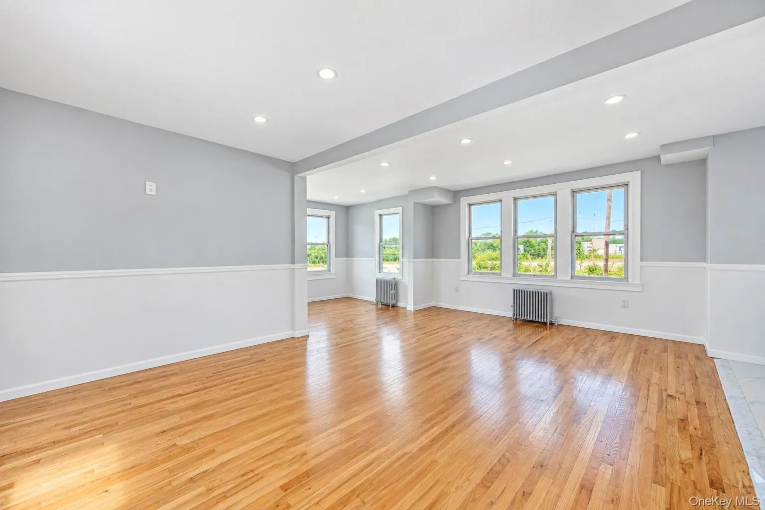 Recessed lighting, wood-finish flooring, multiple windows, two-tone wall treatment, and an open layout Recessed lighting, wood-finish flooring, multiple windows, two-tone wall treatment, and an open layout