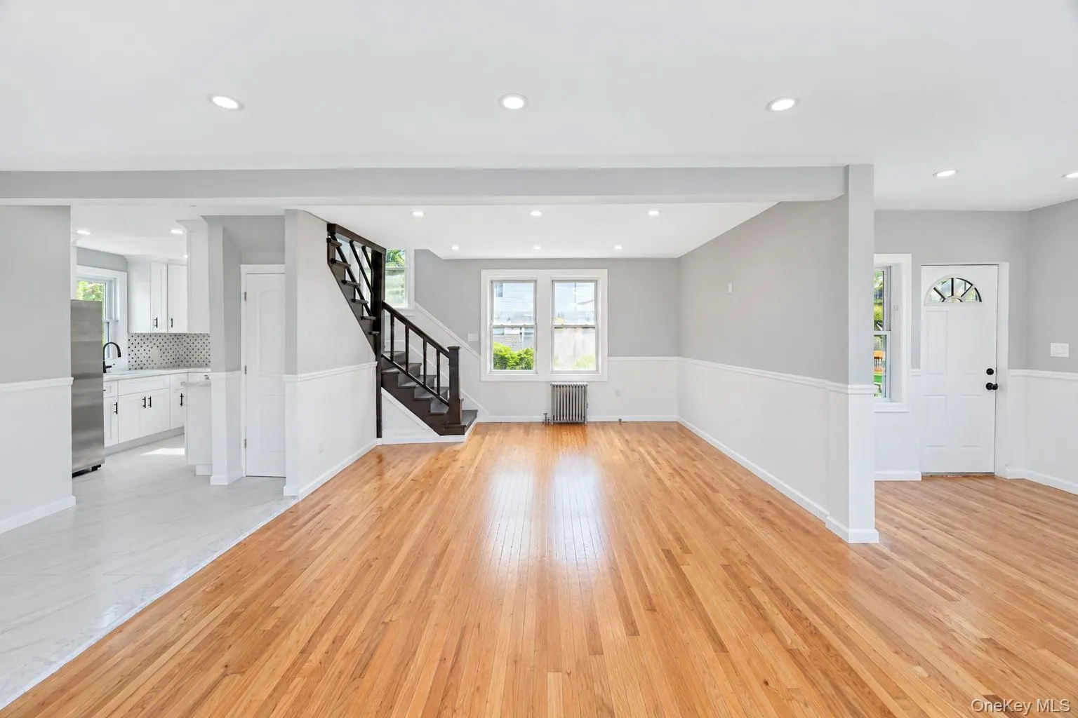 Hardwood flooring, recessed lighting, and a white paneled entrance door Hardwood flooring, recessed lighting, and a white paneled entrance door