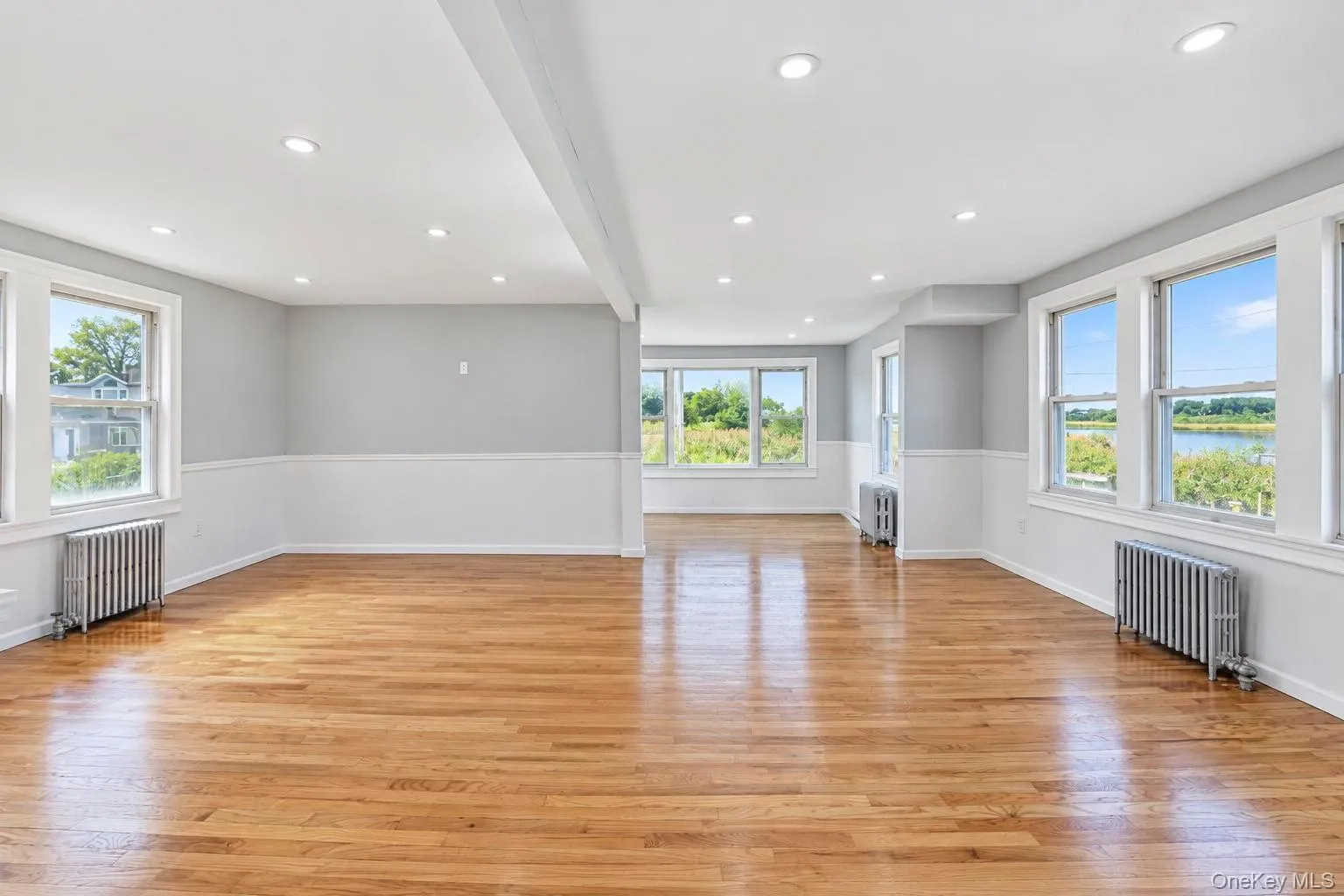 Hardwood flooring throughout, recessed ceiling lighting, multiple windows, and a two-tone wall finish Hardwood flooring throughout, recessed ceiling lighting, multiple windows, and a two-tone wall finish