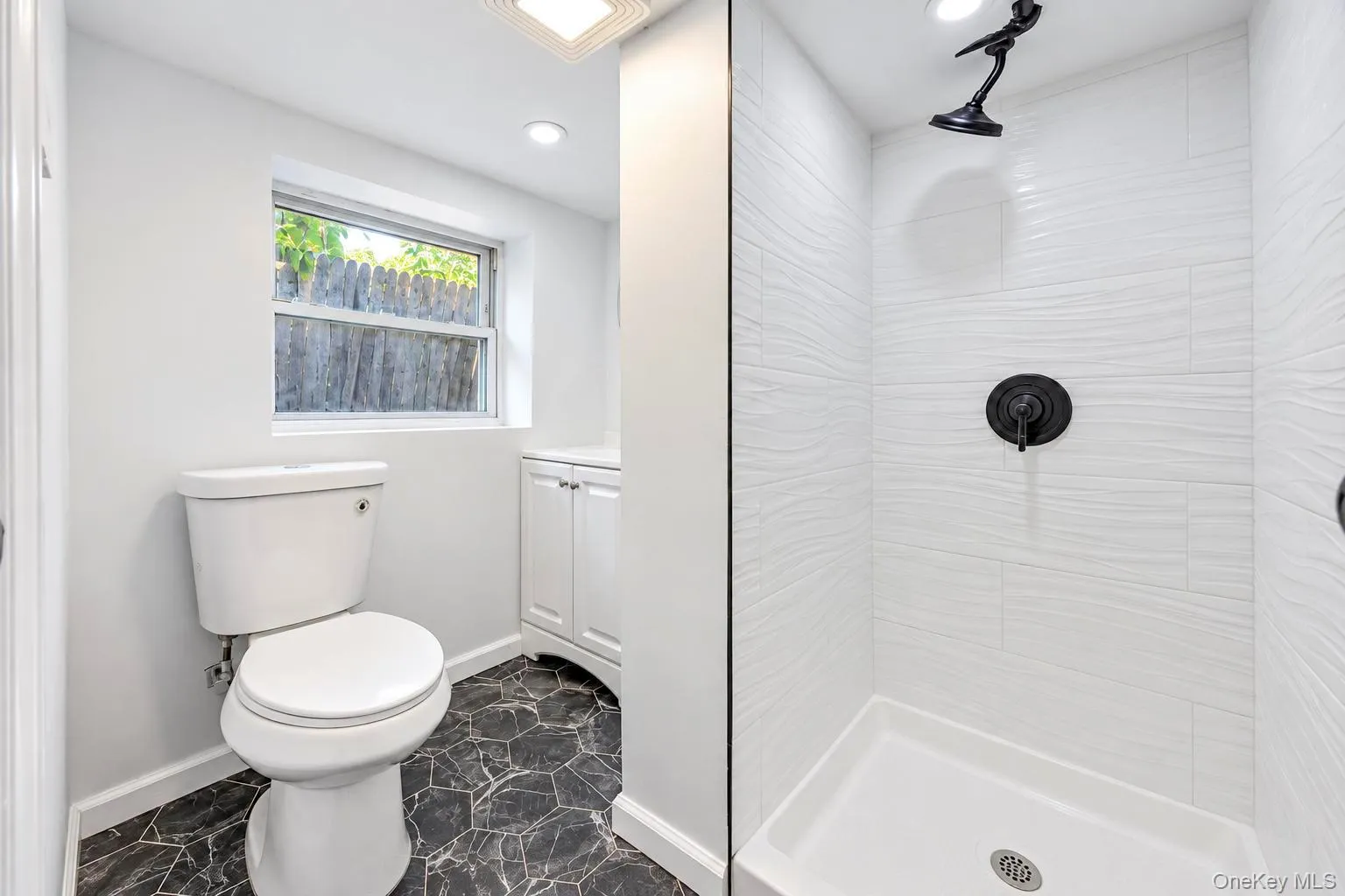 Bathroom featuring a commode, recessed lighting, and a window Bathroom featuring a commode, recessed lighting, and a window