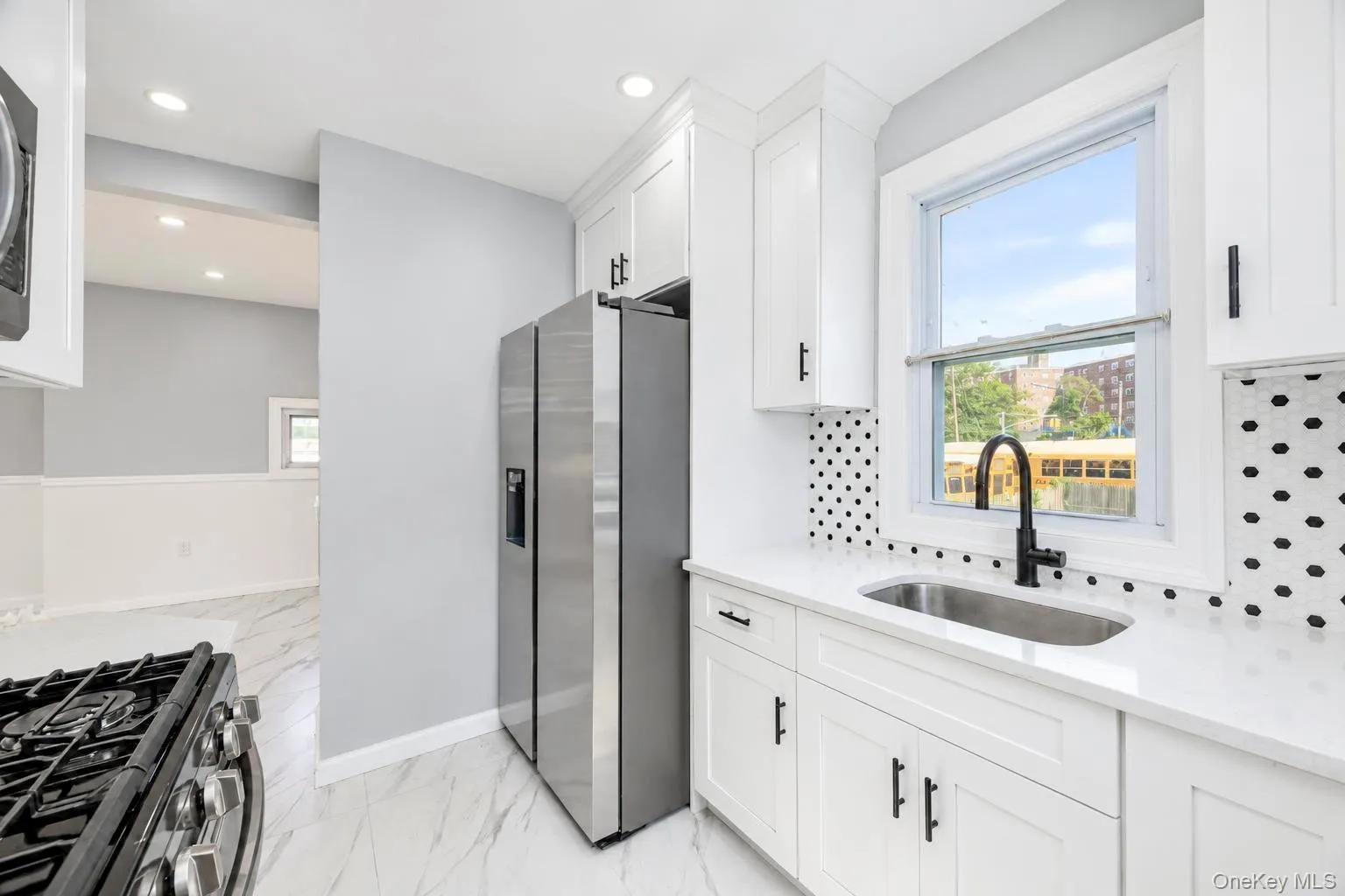 White shaker cabinetry with matte black hardware, stainless steel appliances, a black-spotted backsplash, and a black gooseneck faucet White shaker cabinetry with matte black hardware, stainless steel appliances, a black-spotted backsplash, and a black gooseneck faucet