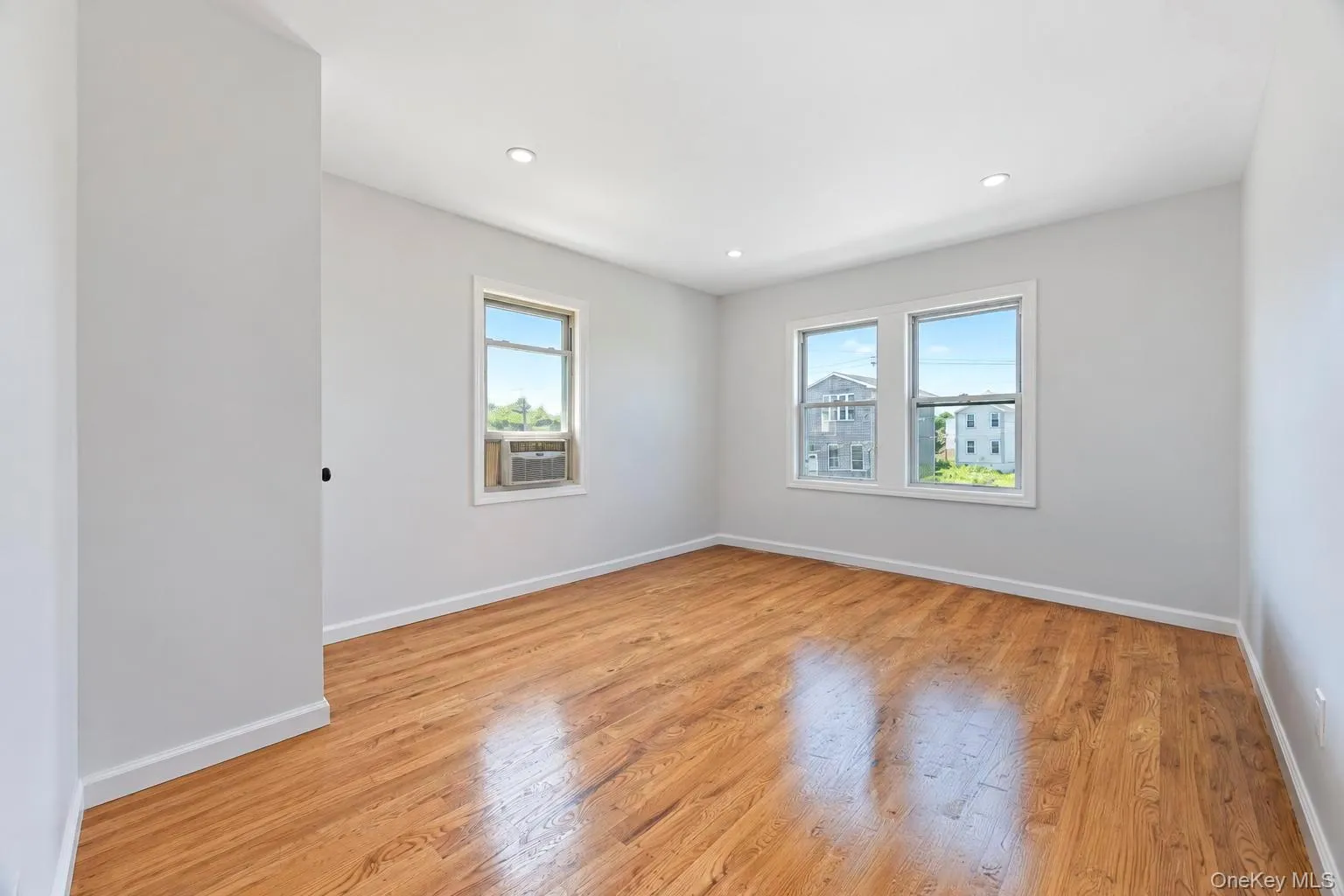 Hardwood flooring, recessed lighting, multiple windows, and light gray walls Hardwood flooring, recessed lighting, multiple windows, and light gray walls