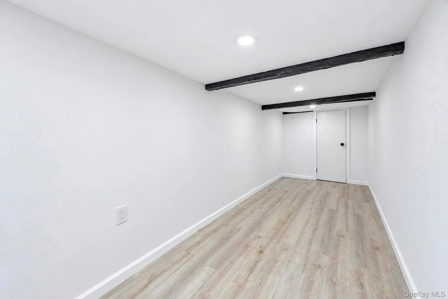 Recessed ceiling lighting, exposed ceiling beams, light wood-finish flooring, white walls, and white trim Recessed ceiling lighting, exposed ceiling beams, light wood-finish flooring, white walls, and white trim