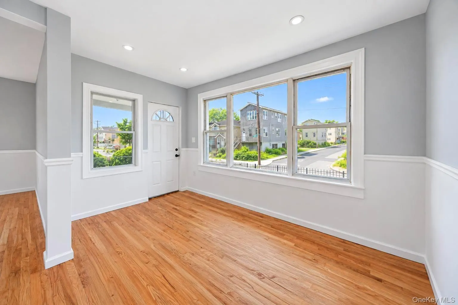 Hardwood flooring, recessed lighting, white wainscoting, white trim, and a paneled entry door Hardwood flooring, recessed lighting, white wainscoting, white trim, and a paneled entry door