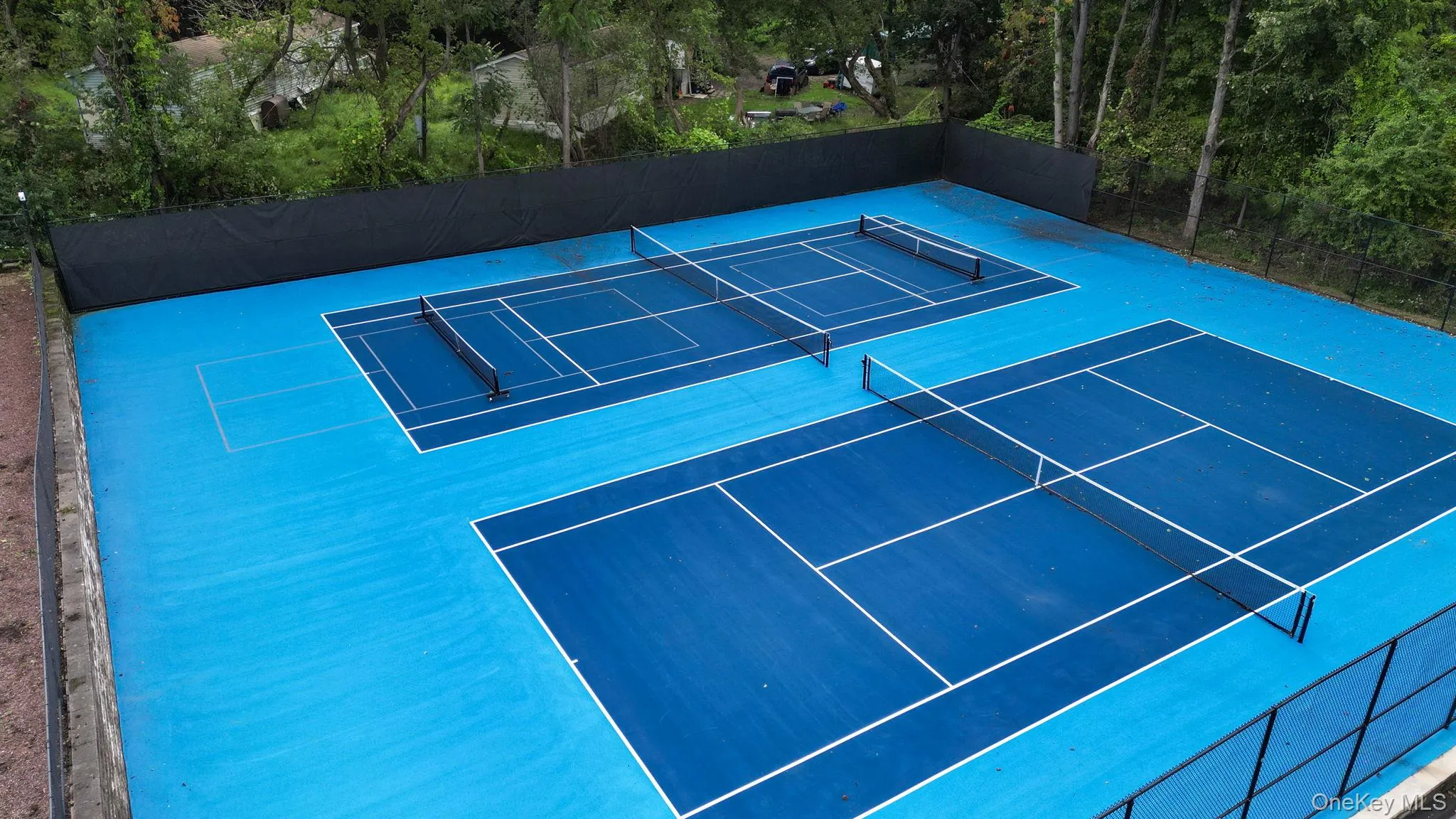 Two full-sized tennis courts with blue surfacing and white line markings Two full-sized tennis courts with blue surfacing and white line markings