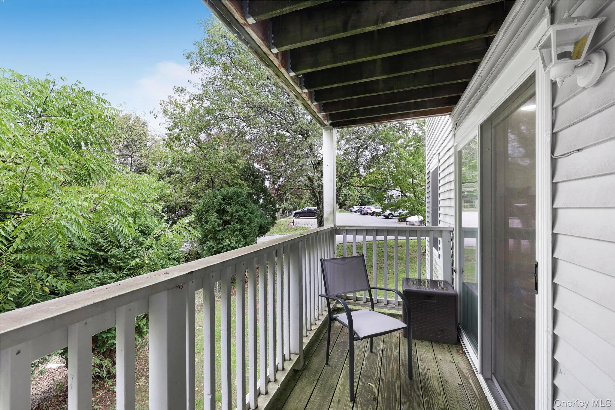 Private balcony with wood flooring, white railing, and sliding glass door access Private balcony with wood flooring, white railing, and sliding glass door access