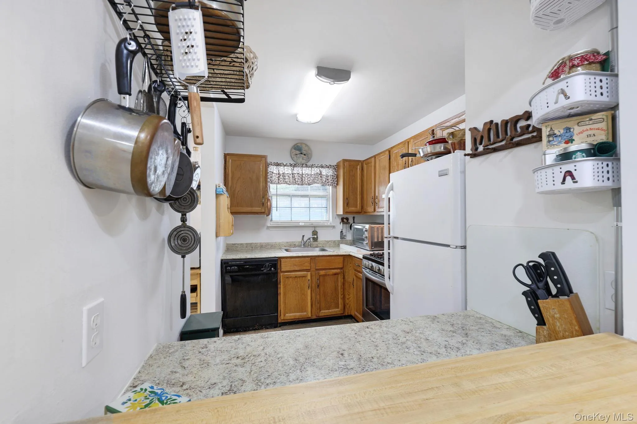 Kitchen featuring wood cabinetry, a white refrigerator, a black dishwasher, and a stainless steel range Kitchen featuring wood cabinetry, a white refrigerator, a black dishwasher, and a stainless steel range