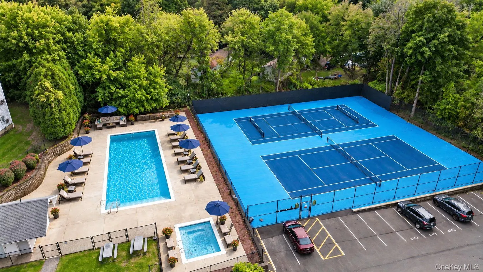 Expansive outdoor amenities featuring a rectangular swimming pool, separate spa, two tennis courts, and a paved parking area pool shown opened with AI Expansive outdoor amenities featuring a rectangular swimming pool, separate spa, two tennis courts, and a paved parking area pool shown opened with AI