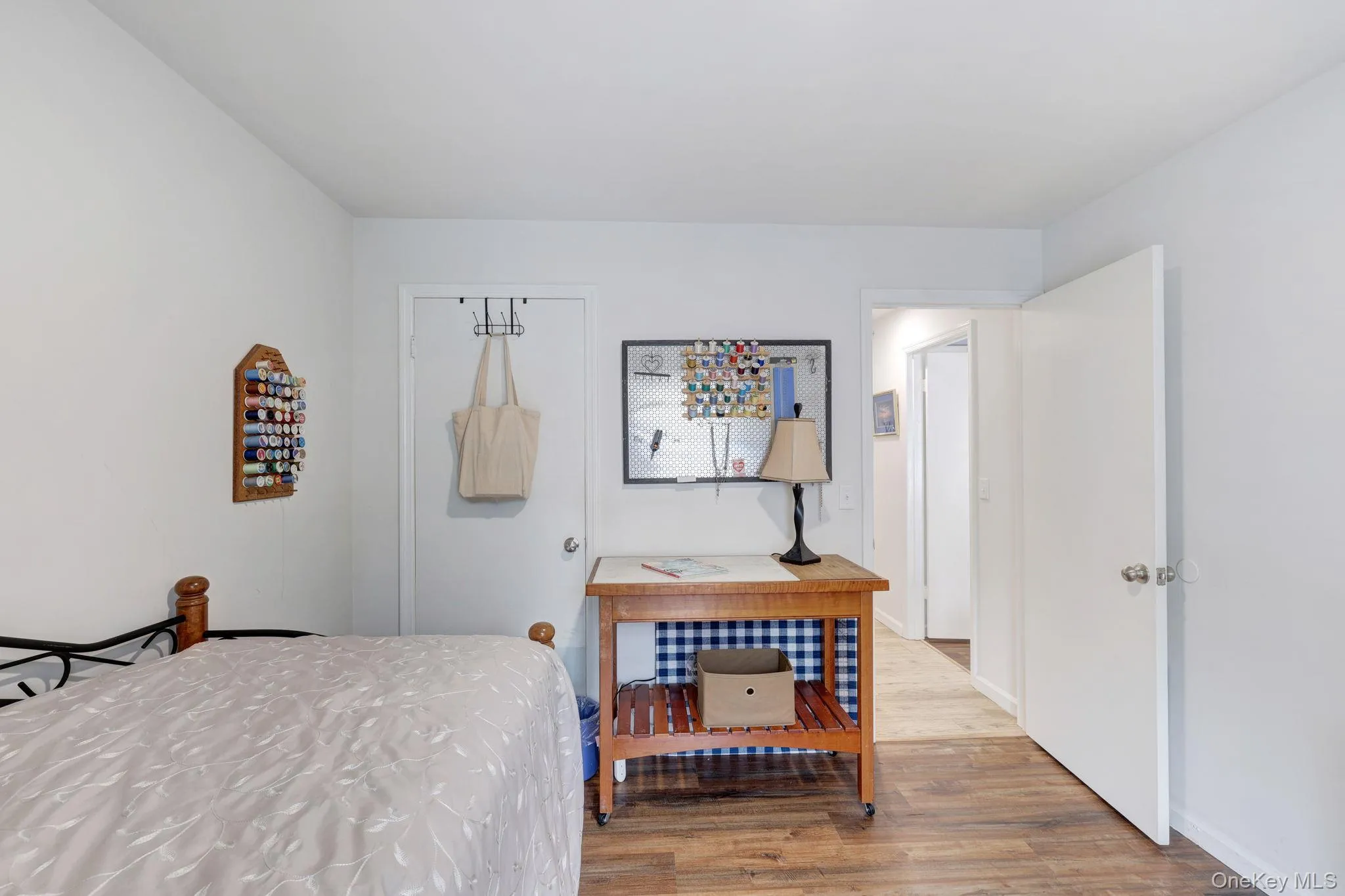 Wood-finish flooring throughout, white walls, and a white interior door with a silver-tone knob Wood-finish flooring throughout, white walls, and a white interior door with a silver-tone knob