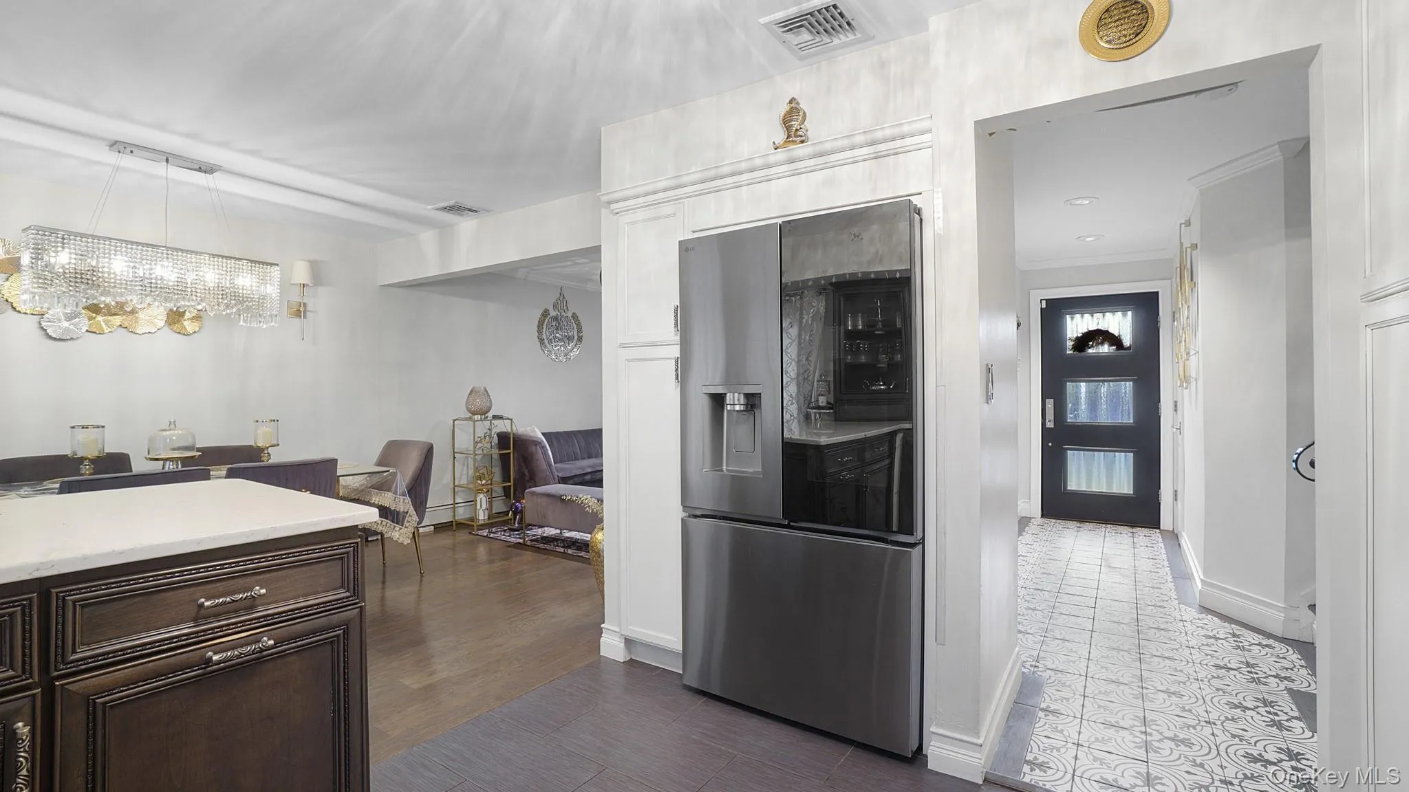 Kitchen featuring stainless steel fridge with ice dispenser, light countertops, dark brown cabinets, decorative light fixtures, and ornamental molding Kitchen featuring stainless steel fridge with ice dispenser, light countertops, dark brown cabinets, decorative light fixtures, and ornamental molding
