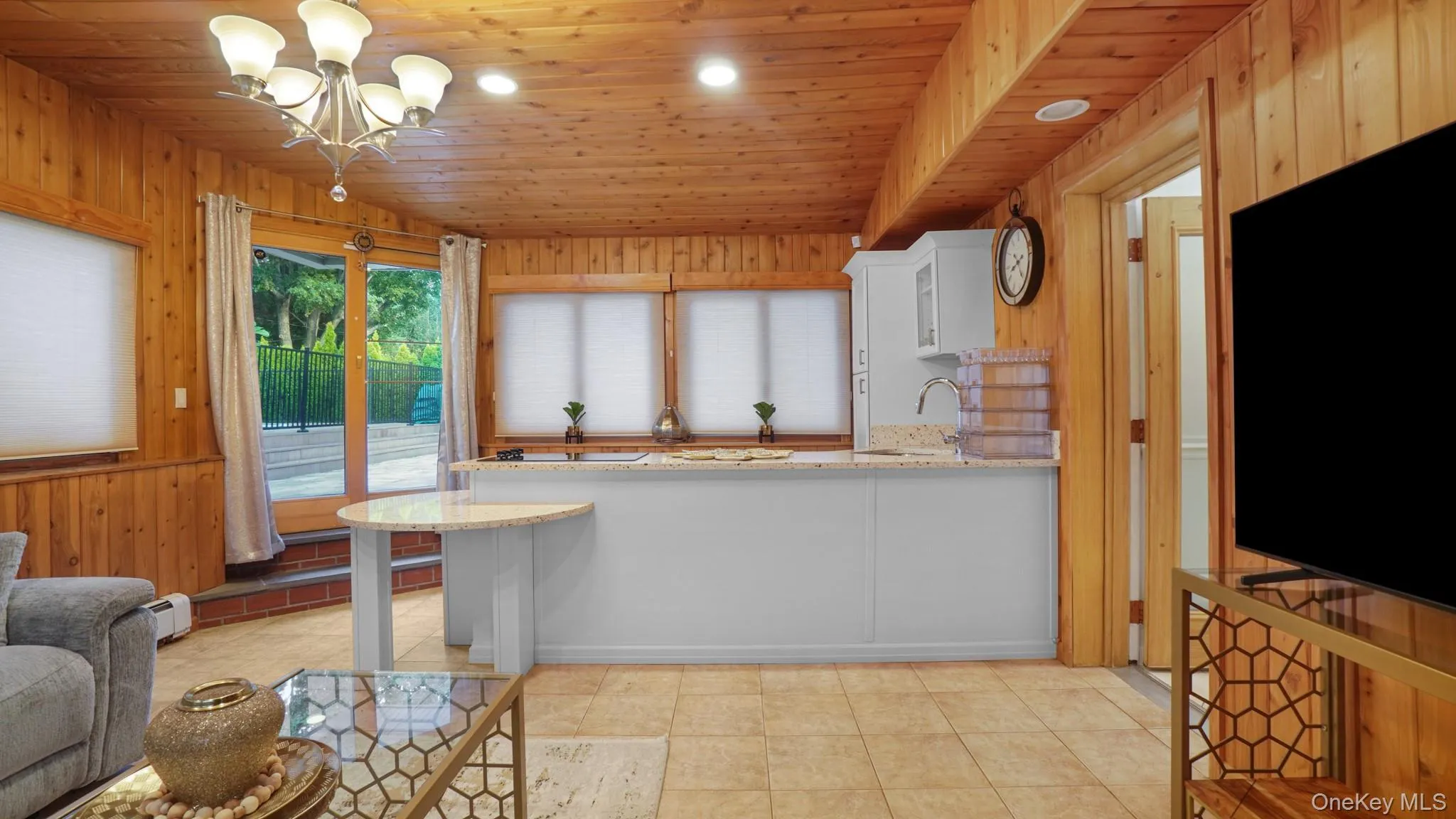 Kitchen featuring wooden walls, wooden ceiling, light stone countertops, a peninsula, and a baseboard radiator Kitchen featuring wooden walls, wooden ceiling, light stone countertops, a peninsula, and a baseboard radiator