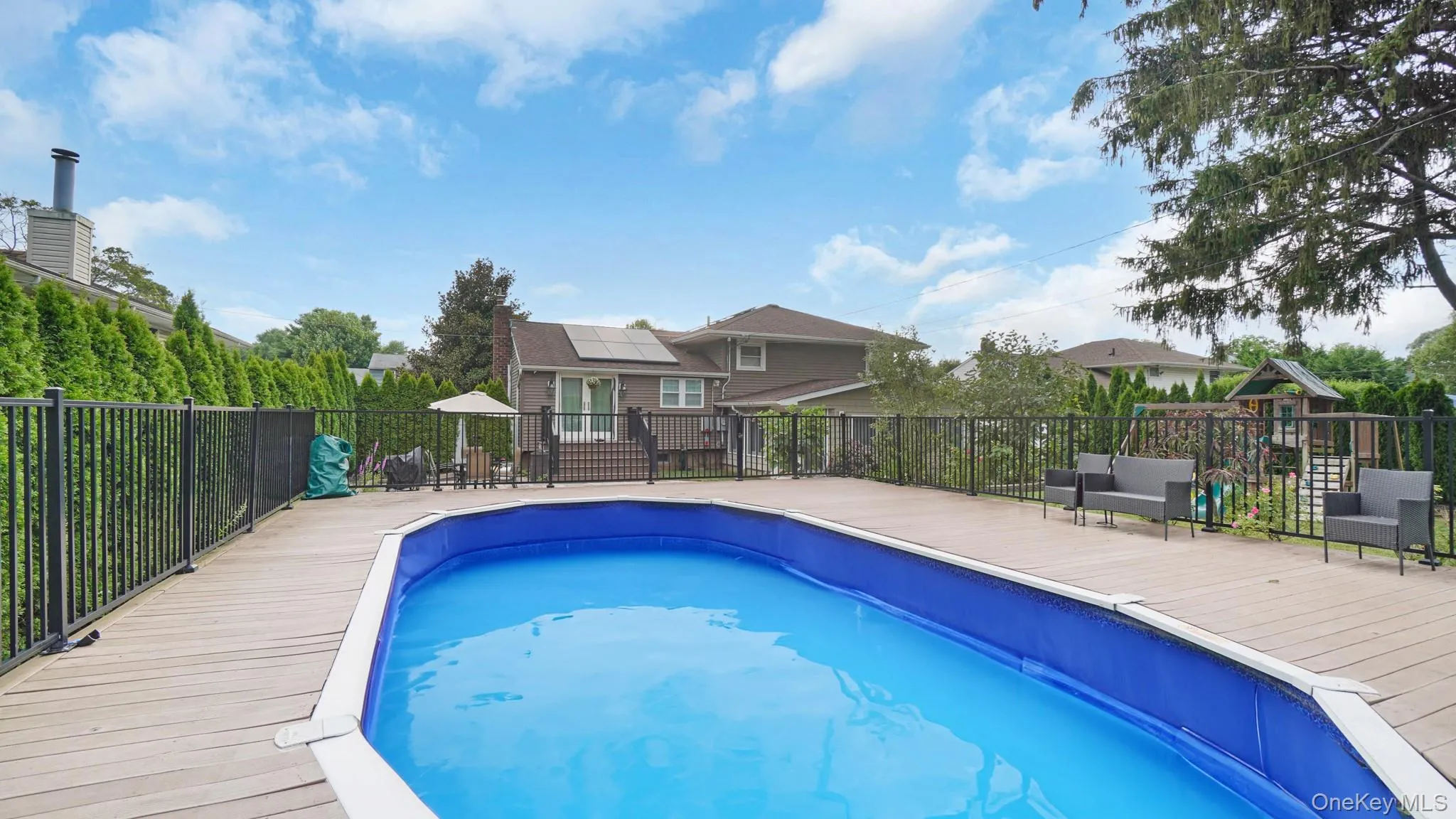 View of pool featuring a playground and a wooden deck View of pool featuring a playground and a wooden deck
