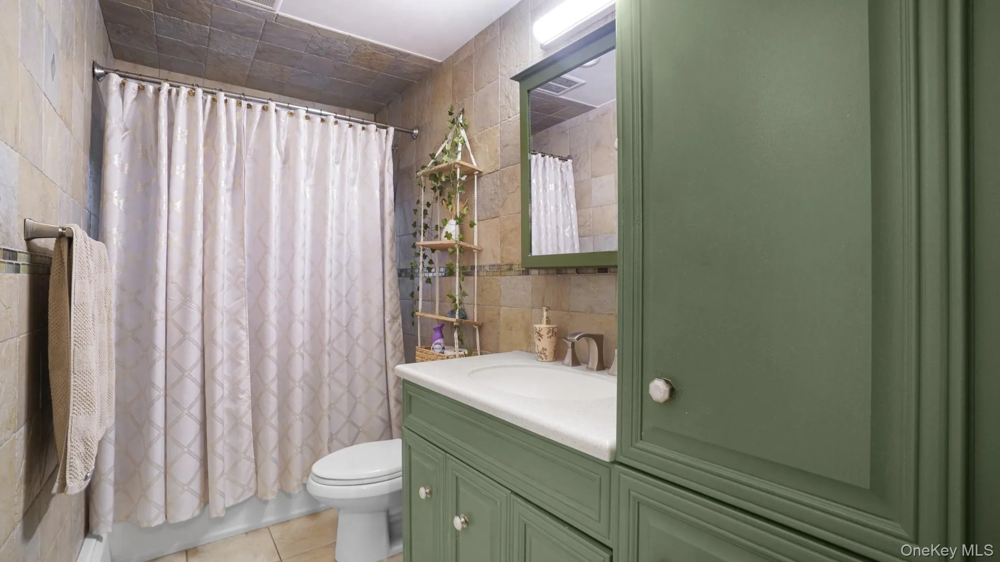 Full bathroom featuring tile walls, vanity, and tile patterned flooring Full bathroom featuring tile walls, vanity, and tile patterned flooring