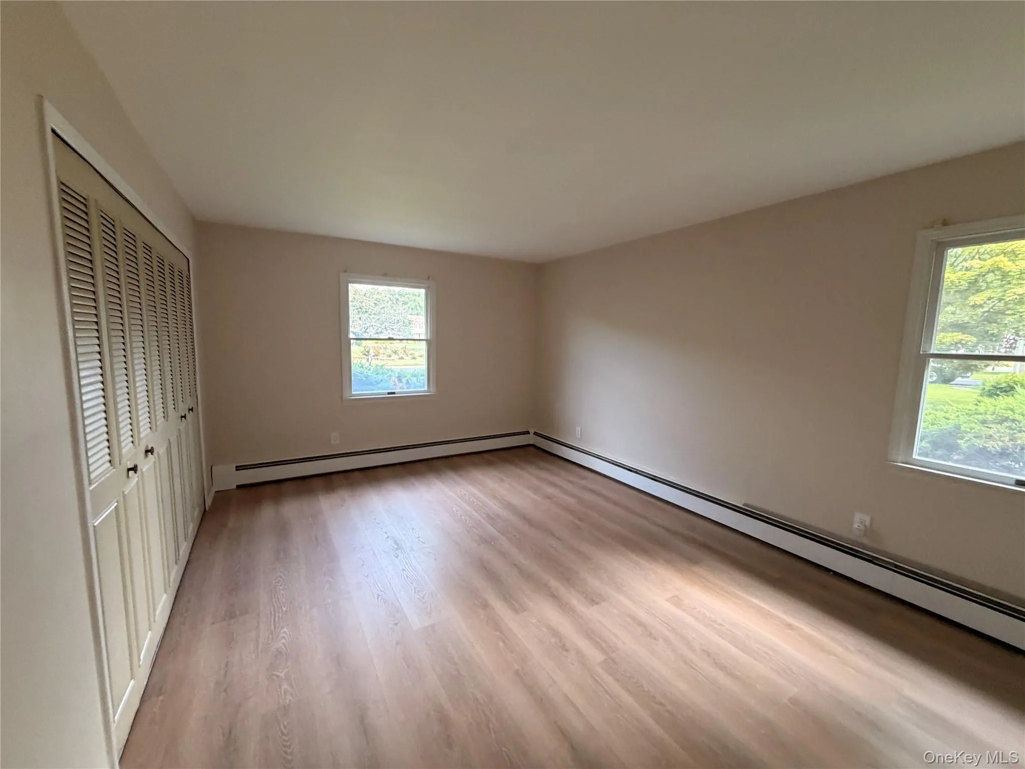 Wood-finish flooring throughout, complemented by two large windows and a full-wall closet with louvered bifold doors Wood-finish flooring throughout, complemented by two large windows and a full-wall closet with louvered bifold doors