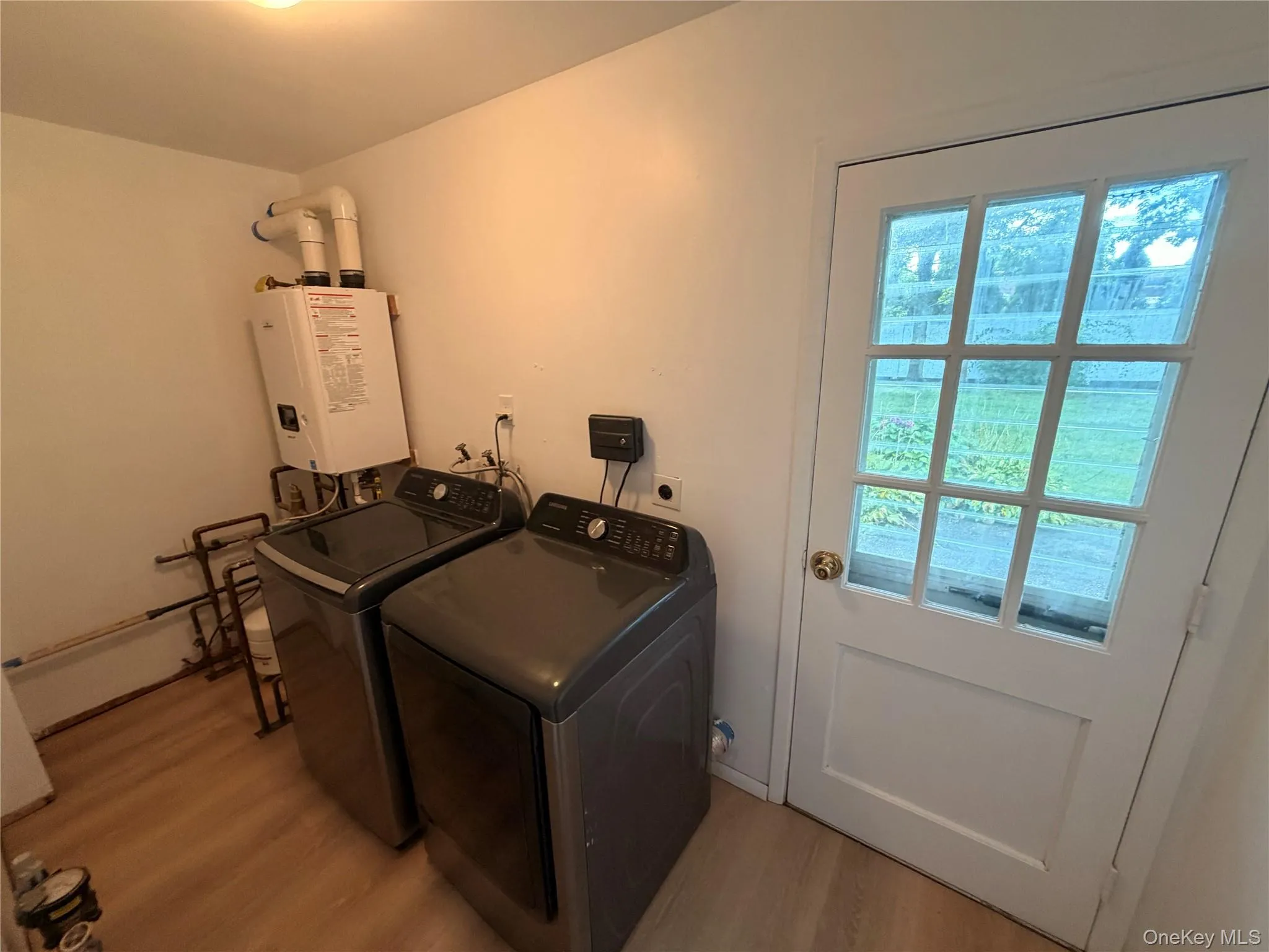 Wood-finish flooring with a white paneled door featuring multiple glass lites Wood-finish flooring with a white paneled door featuring multiple glass lites