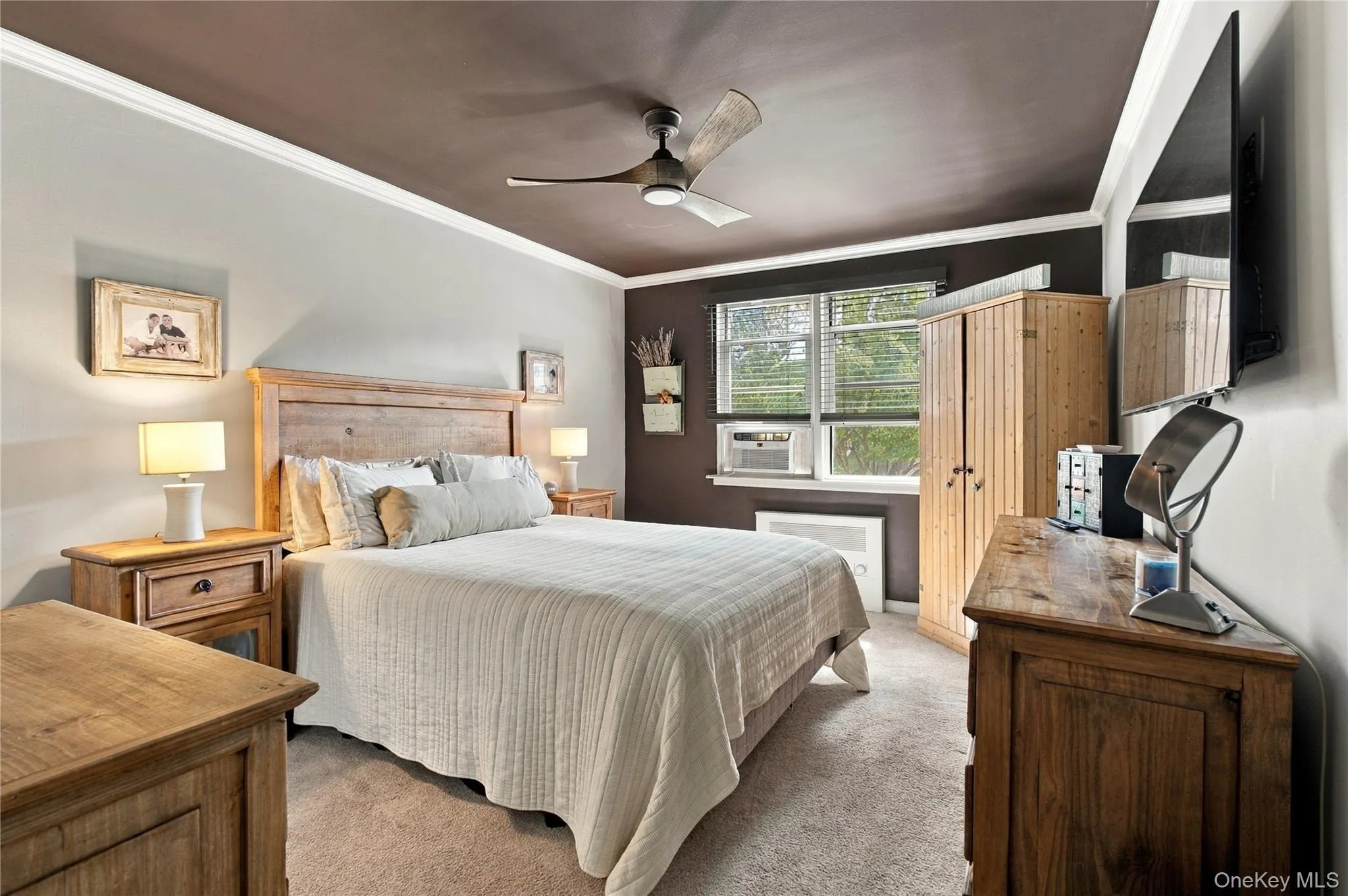 The spacious primary bedroom is bright and inviting featuring custom radiator covers and a dedicated air conditioning unit. The spacious primary bedroom is bright and inviting featuring custom radiator covers and a dedicated air conditioning unit.