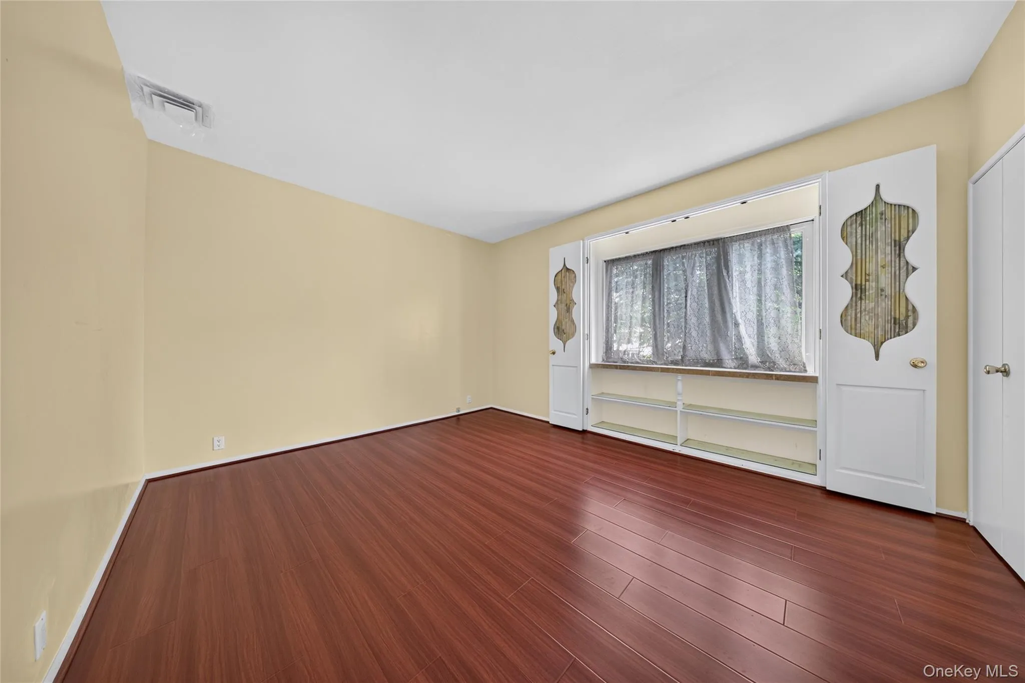 Rich wood-finish flooring, built-in shelving, white trim, and a window with a deep sill Rich wood-finish flooring, built-in shelving, white trim, and a window with a deep sill