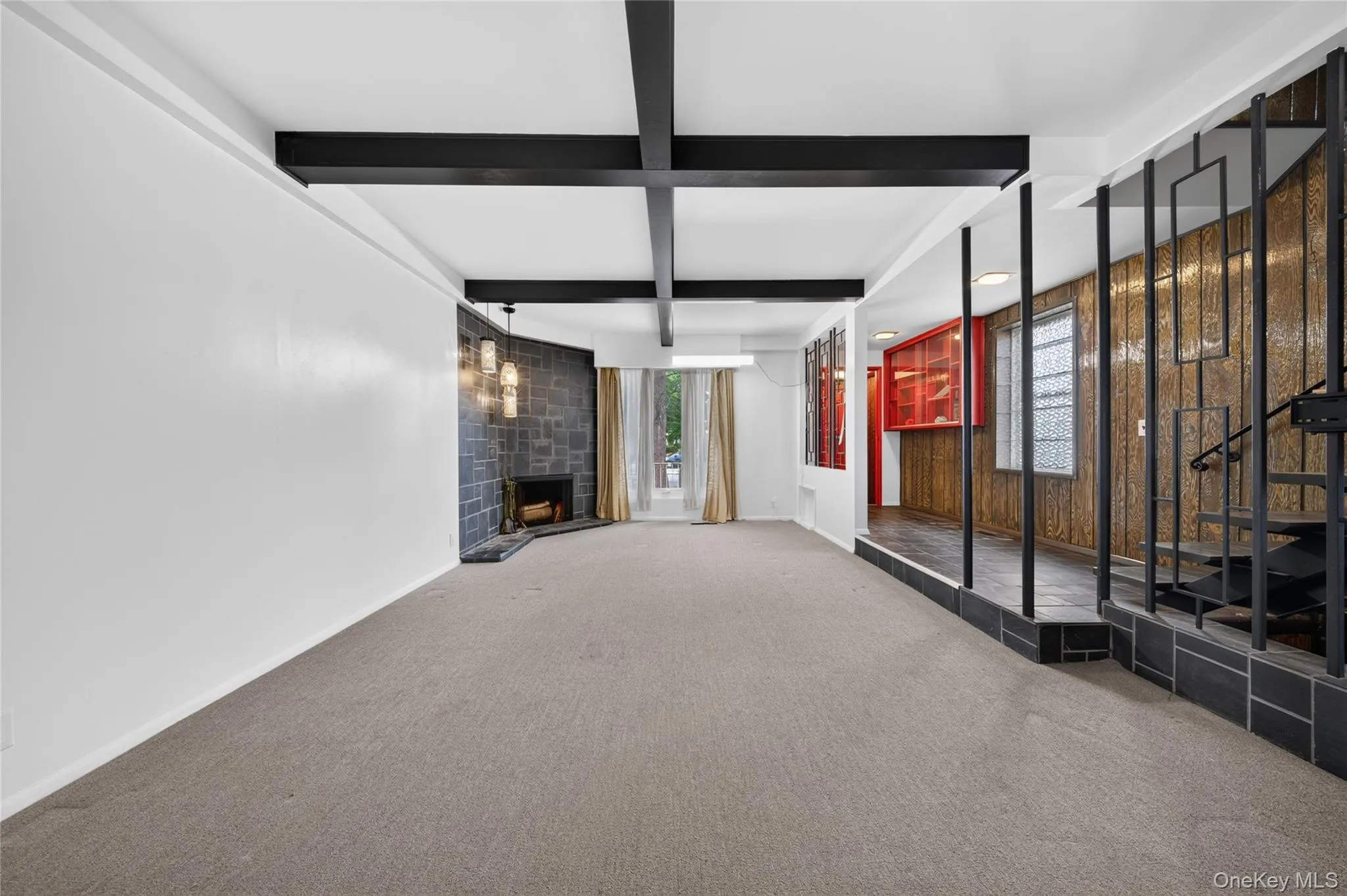 Exposed ceiling beams, integrated fireplace with a stone surround, multi-light pendant fixture, built-in shelving, and a multi-level floor plan with staircase Exposed ceiling beams, integrated fireplace with a stone surround, multi-light pendant fixture, built-in shelving, and a multi-level floor plan with staircase