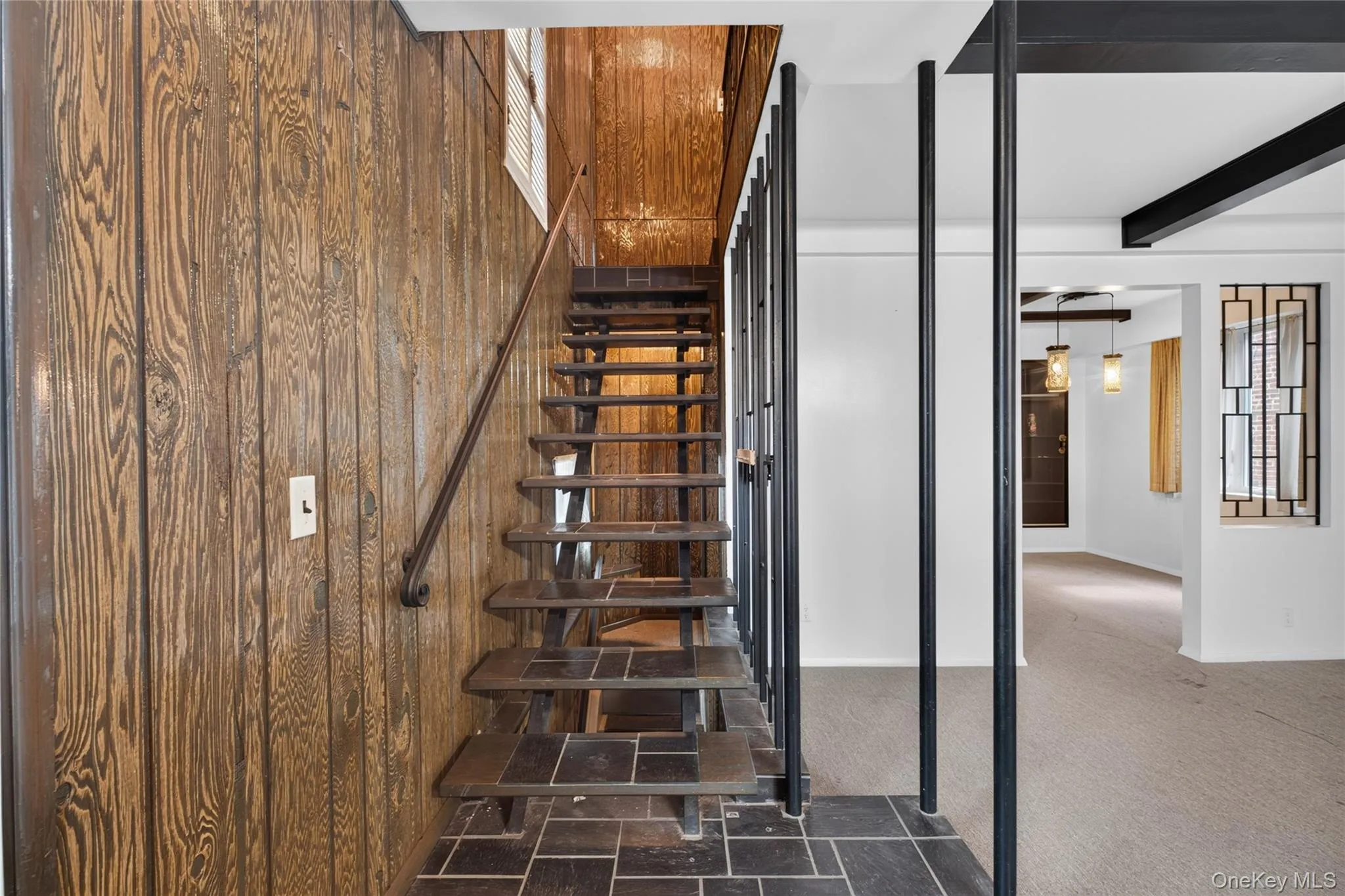 Wood-paneled wall and staircase with a dark wood handrail, leading to an upper level Wood-paneled wall and staircase with a dark wood handrail, leading to an upper level