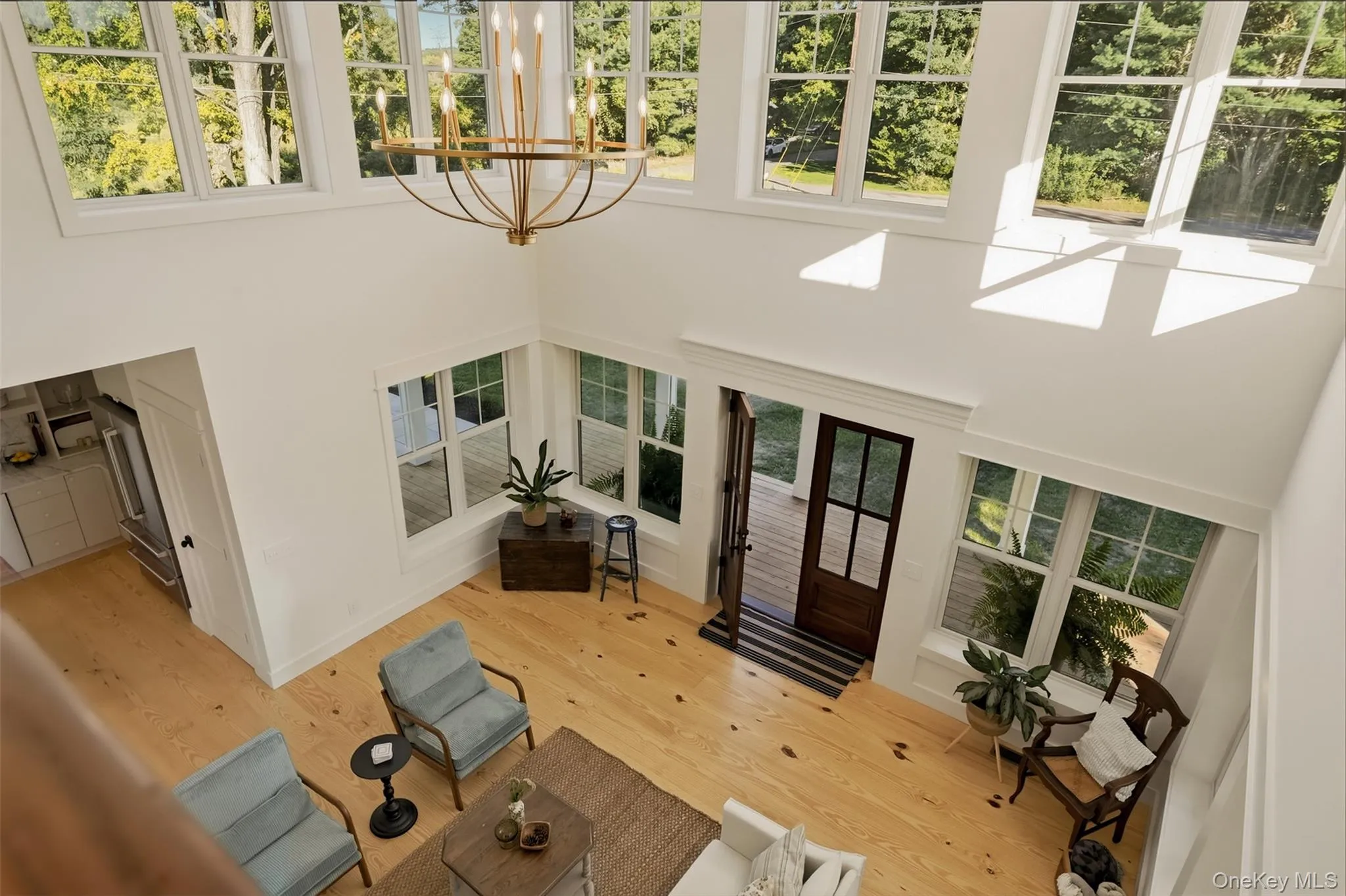 Bird's eye view of the living room with large windows and timeless chandelier Bird's eye view of the living room with large windows and timeless chandelier