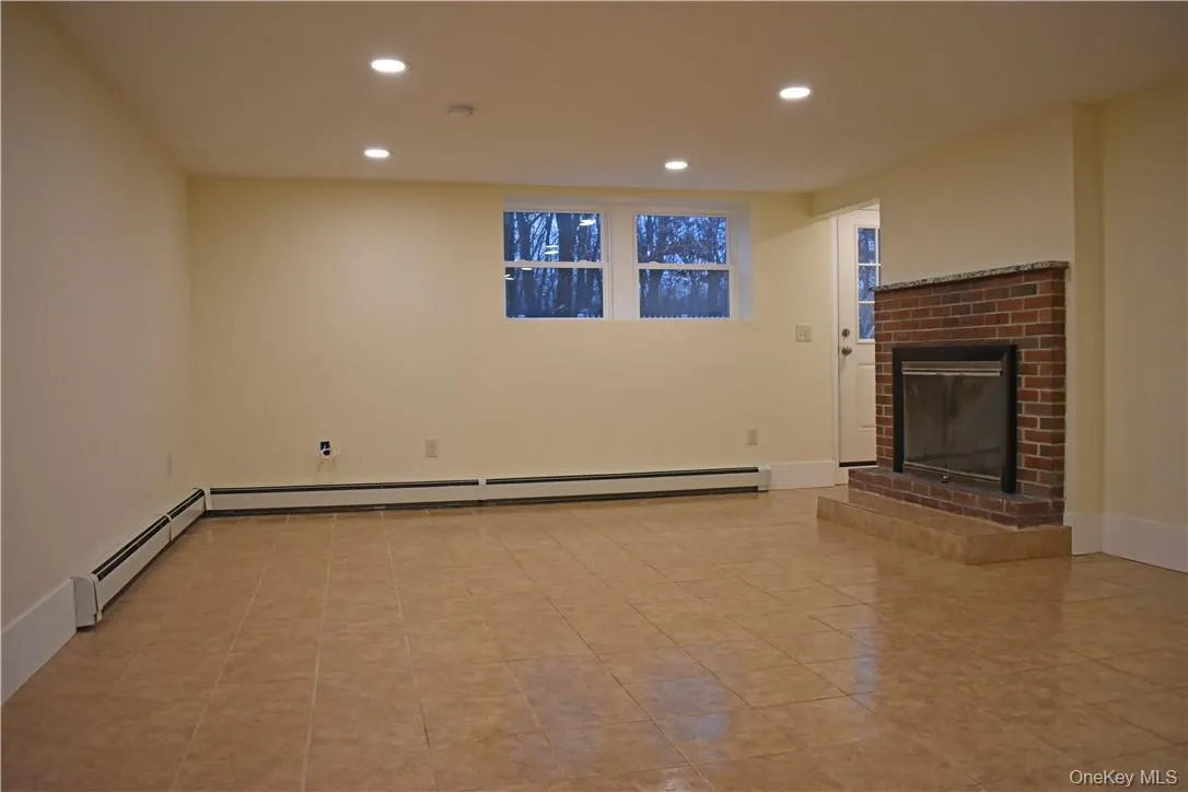 Recessed ceiling lighting, tiled flooring, brick fireplace with hearth, and two windows Recessed ceiling lighting, tiled flooring, brick fireplace with hearth, and two windows