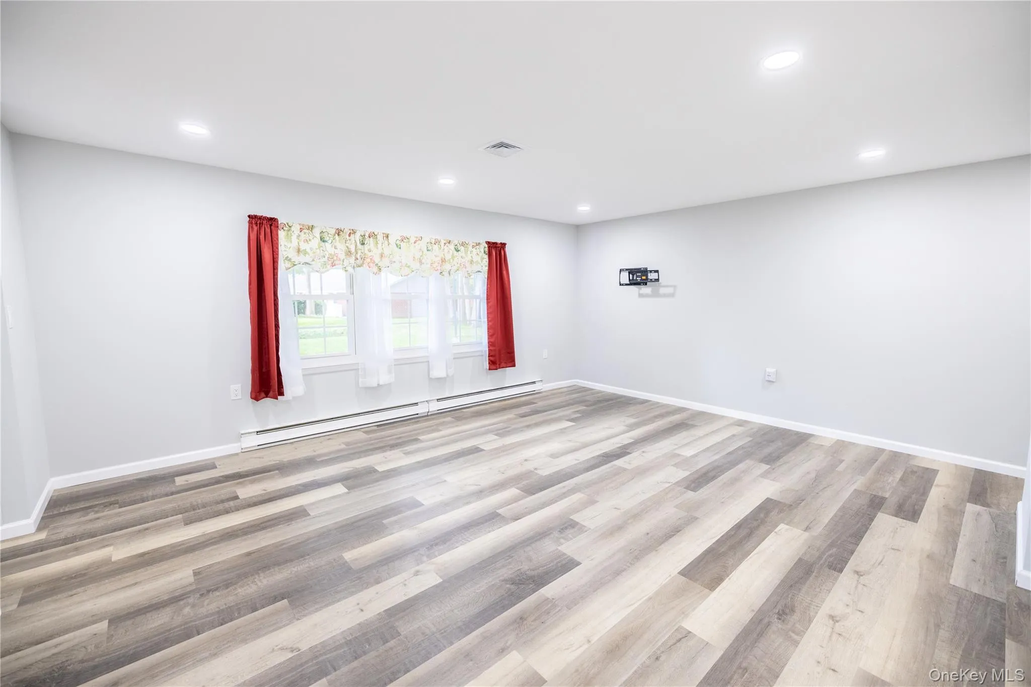 Recessed lighting, wood-finish flooring, light gray wall color, and multiple windows Recessed lighting, wood-finish flooring, light gray wall color, and multiple windows