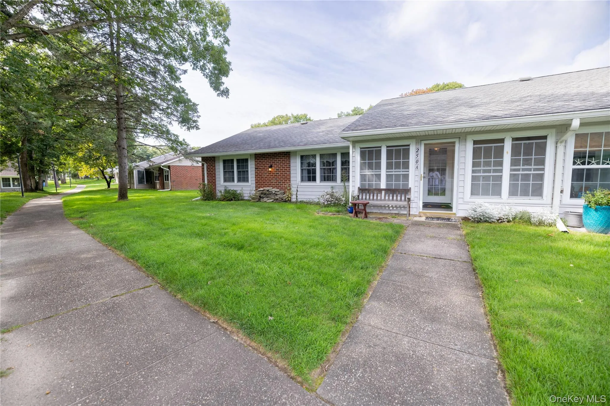 White siding exterior with a brick accent, front entry sunroom, and a concrete pathway White siding exterior with a brick accent, front entry sunroom, and a concrete pathway