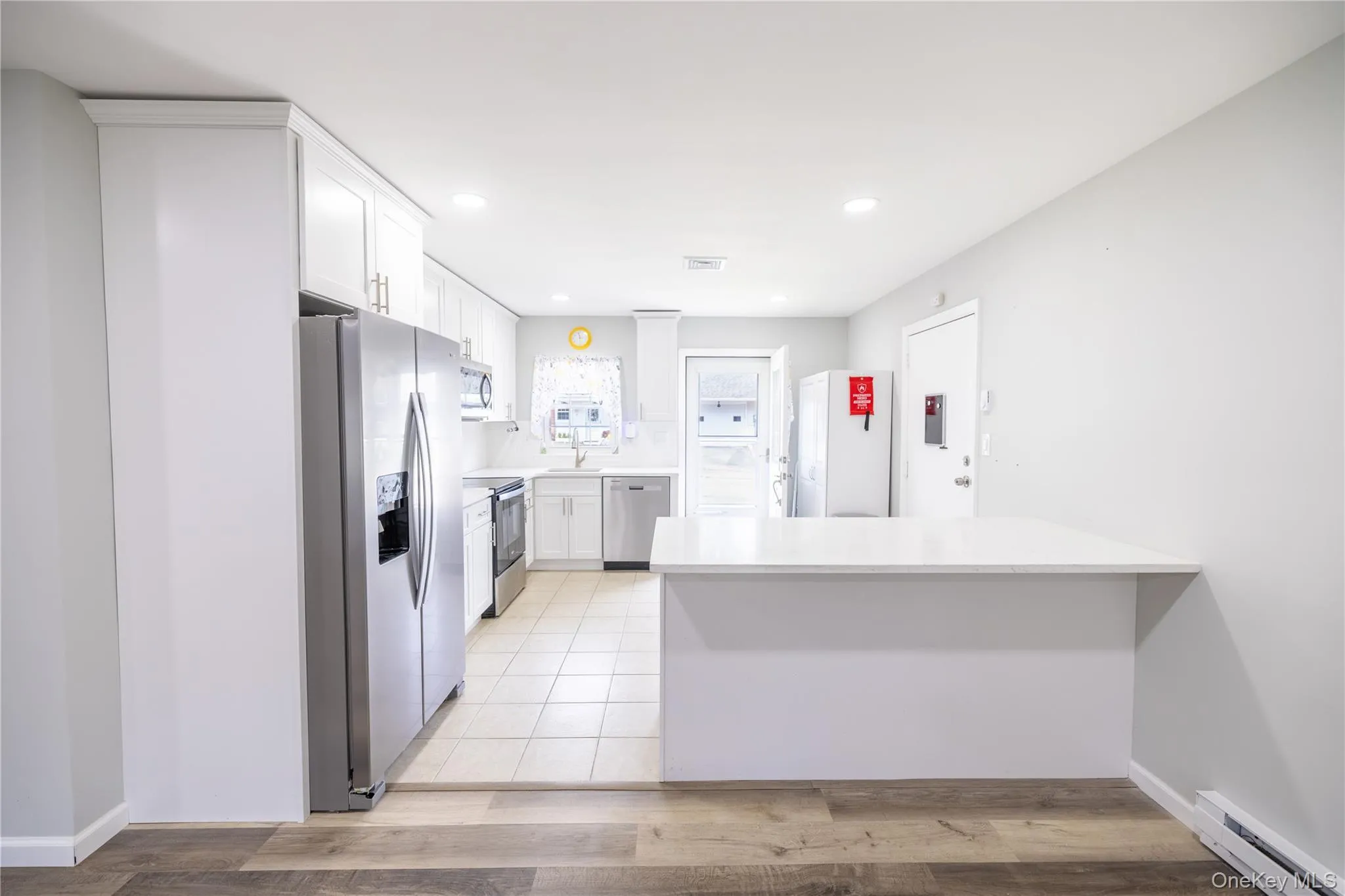 Kitchen featuring white cabinetry, stainless steel appliances, tiled flooring, and a breakfast bar Kitchen featuring white cabinetry, stainless steel appliances, tiled flooring, and a breakfast bar