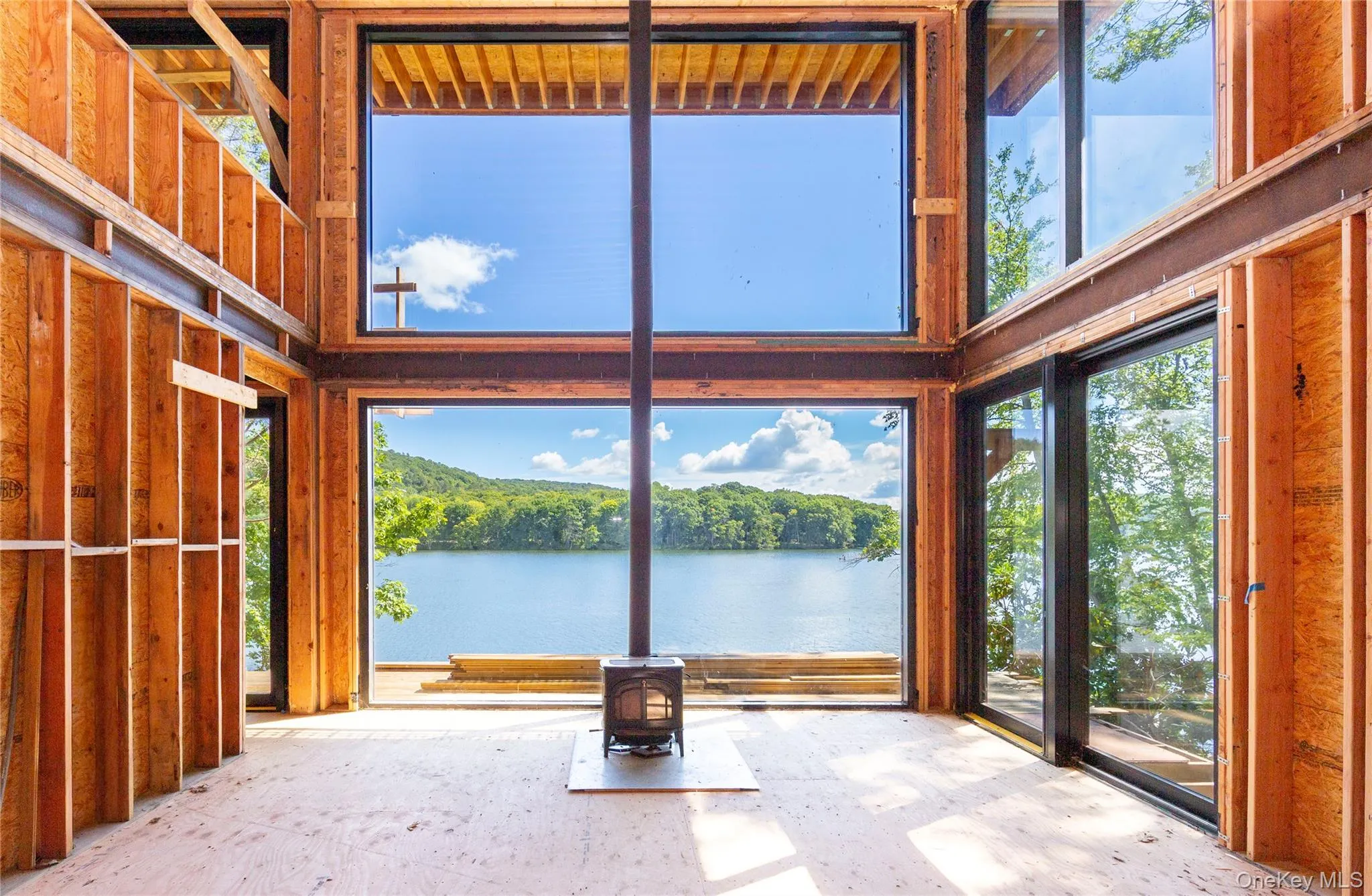 Inside, the main level is defined by a centered wood-burning stove that aligns with the window mullions, creating the illusion of one unbroken wall of glass. Inside, the main level is defined by a centered wood-burning stove that aligns with the window mullions, creating the illusion of one unbroken wall of glass.