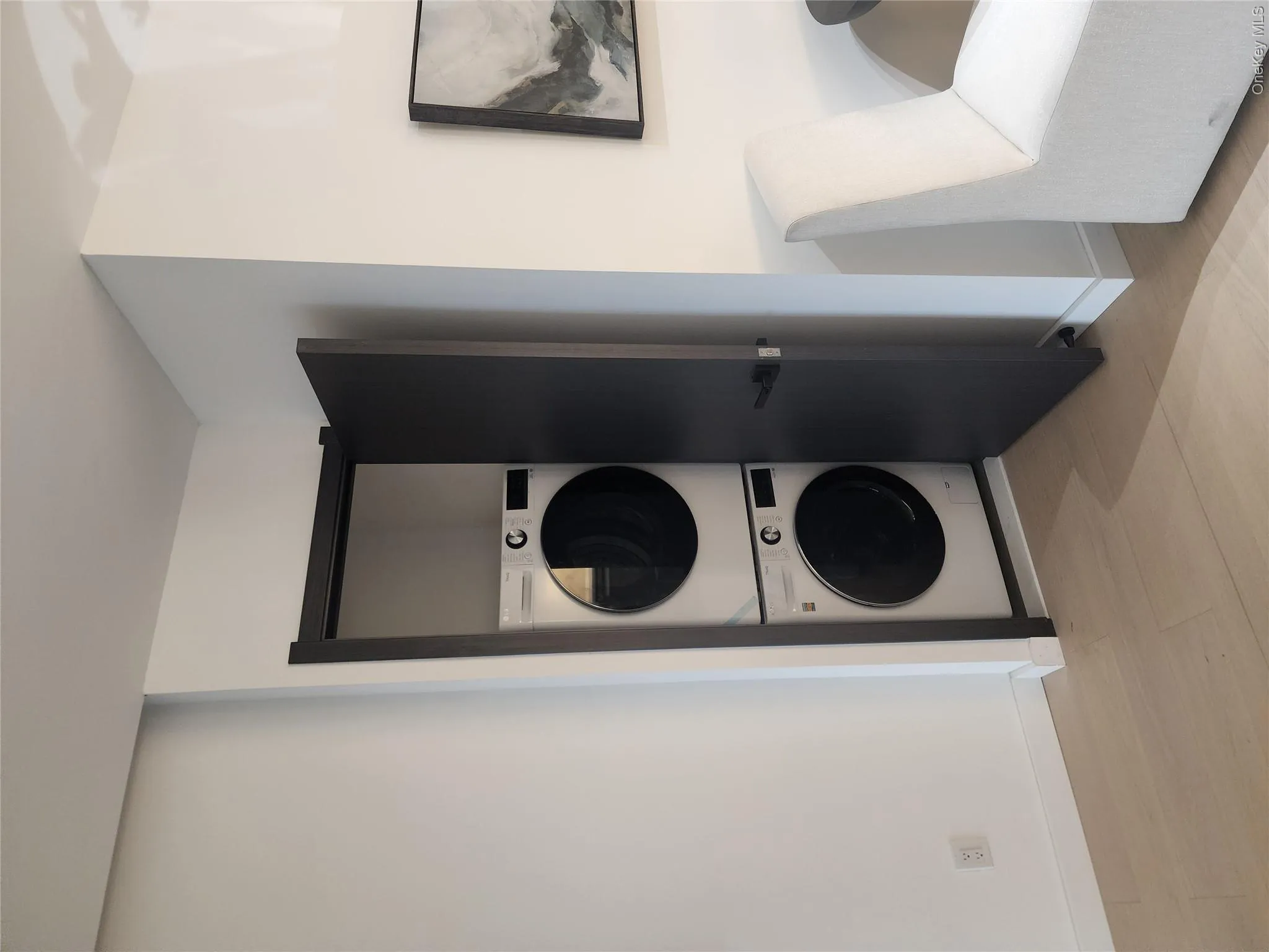 Stacked washer and dryer units within a dedicated closet, light wood-finish flooring, and crisp white walls Stacked washer and dryer units within a dedicated closet, light wood-finish flooring, and crisp white walls