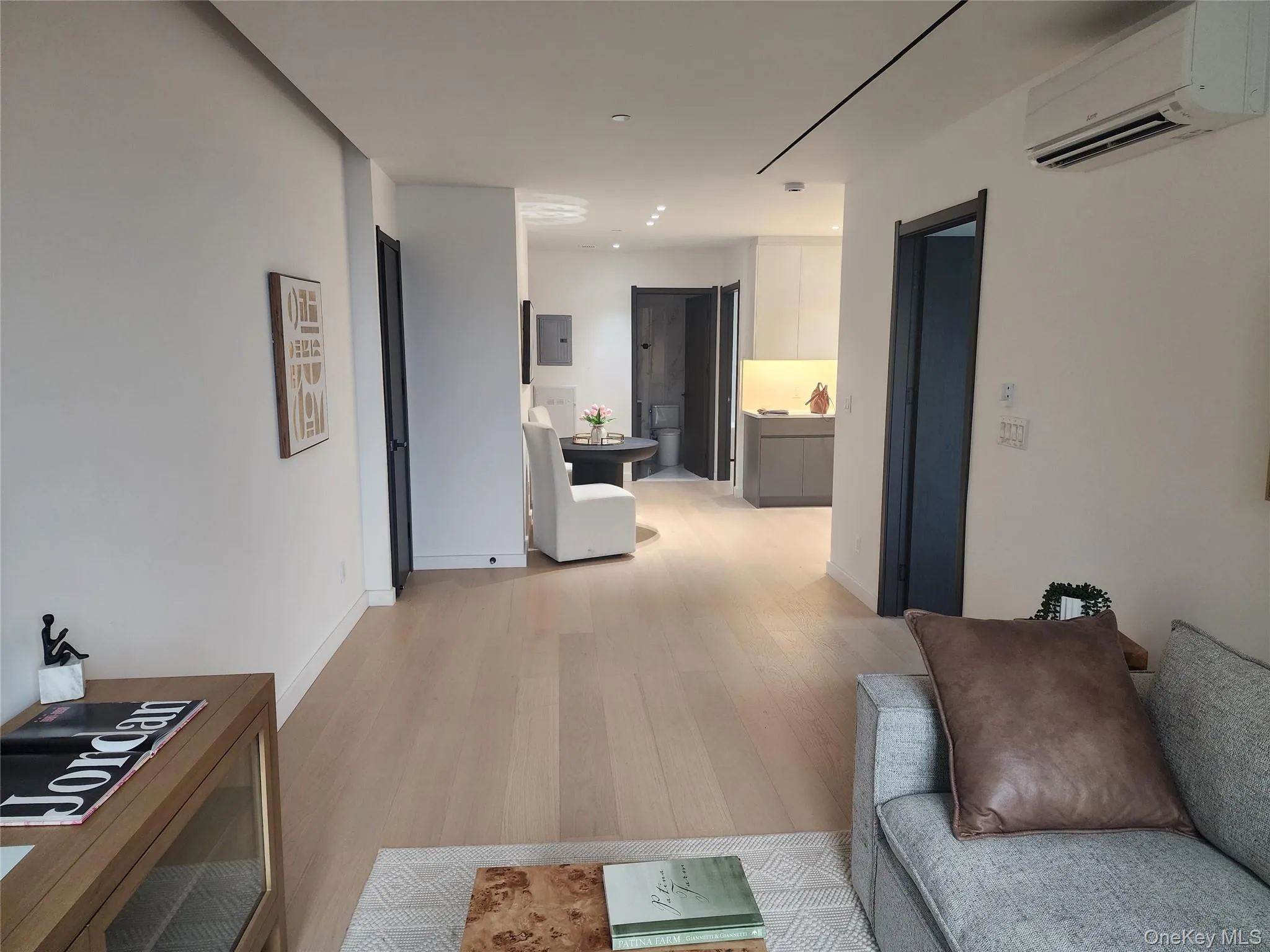 Light wood-finish flooring throughout, white walls, recessed lighting, split-system air conditioning unit, and flush doors with dark trim Light wood-finish flooring throughout, white walls, recessed lighting, split-system air conditioning unit, and flush doors with dark trim