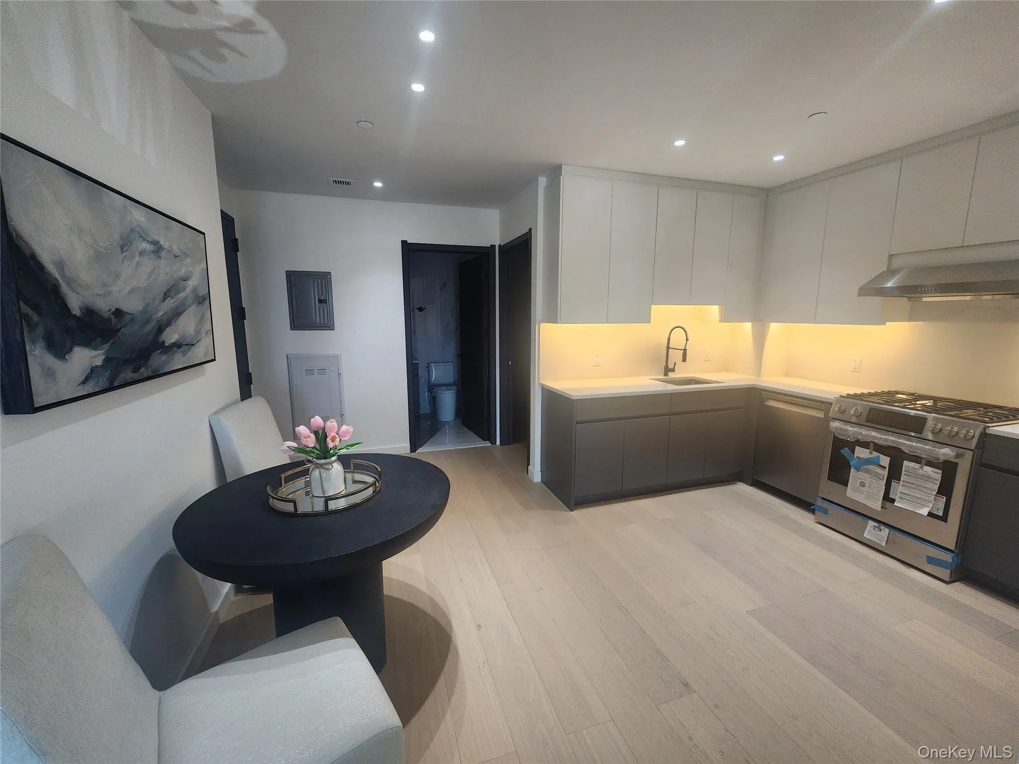Kitchen featuring stainless steel appliances, under-cabinet lighting, wood-finish flooring, and two-tone cabinetry Kitchen featuring stainless steel appliances, under-cabinet lighting, wood-finish flooring, and two-tone cabinetry
