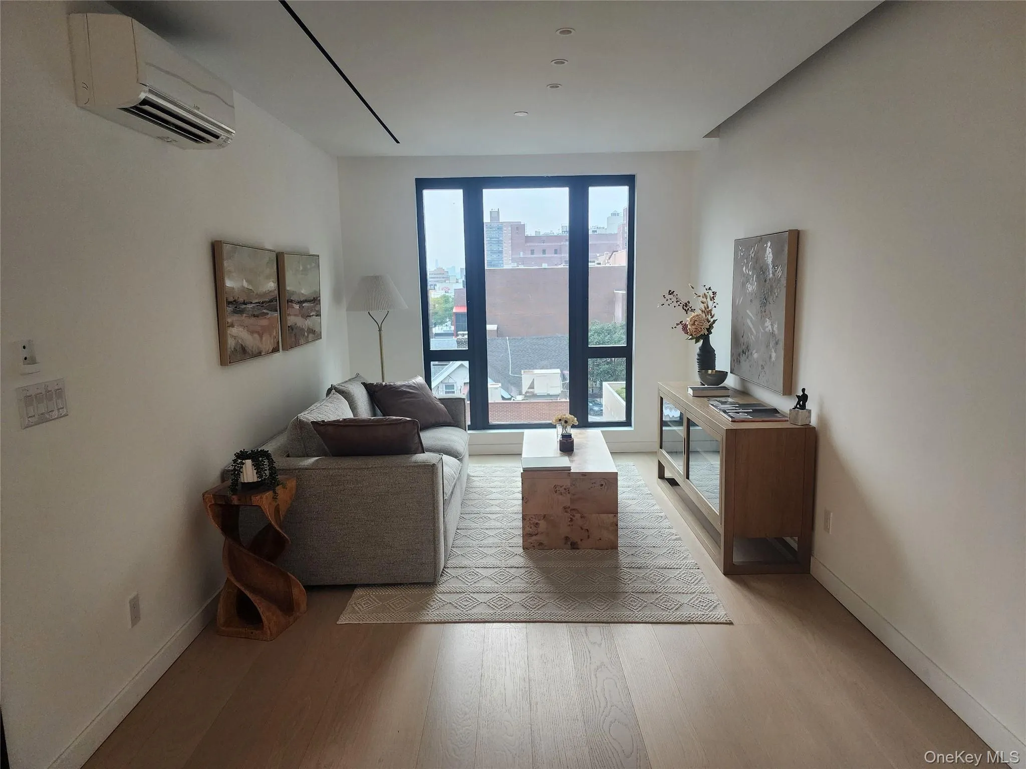Expansive windows with black framing, wood-finish flooring, recessed ceiling lighting, and a wall-mounted climate control unit Expansive windows with black framing, wood-finish flooring, recessed ceiling lighting, and a wall-mounted climate control unit