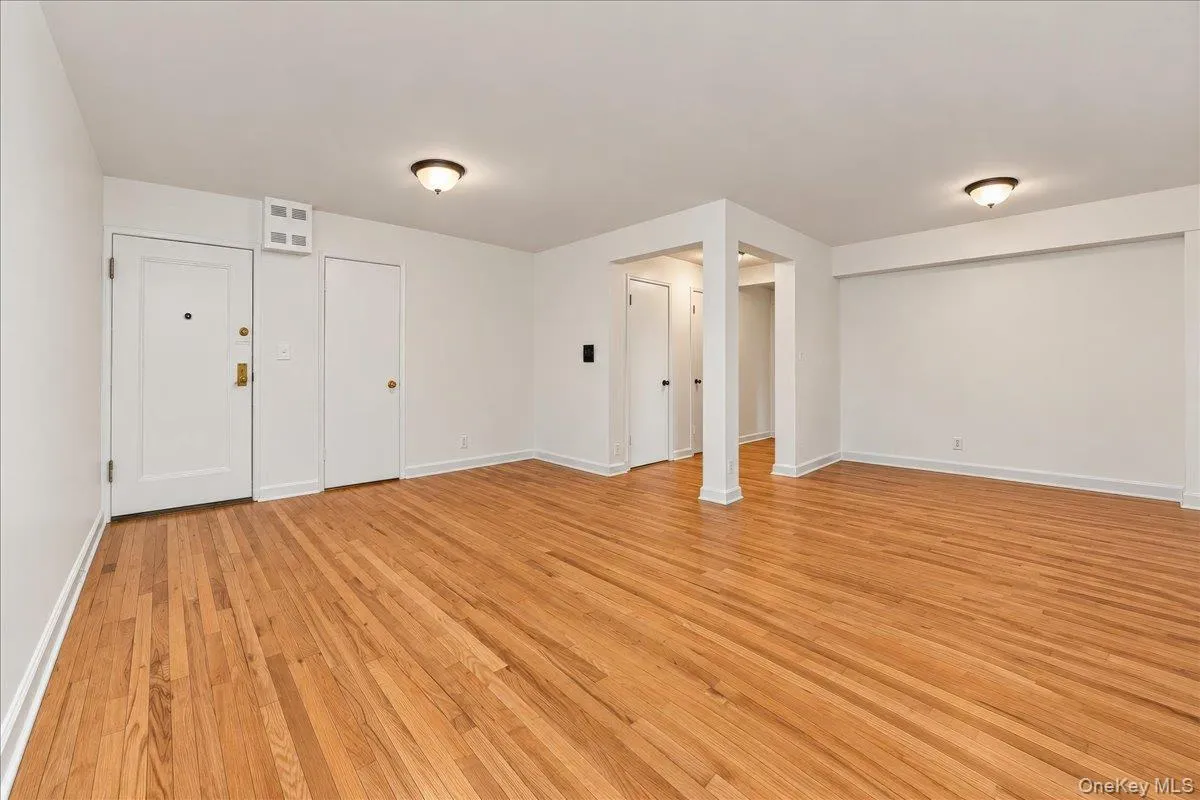 Hardwood flooring, painted white walls, recessed ceiling lighting, a solid panel entry door, and interior doors Hardwood flooring, painted white walls, recessed ceiling lighting, a solid panel entry door, and interior doors