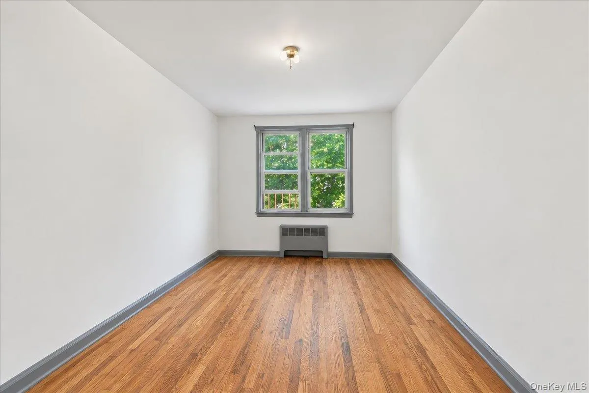 Hardwood flooring, painted walls, window with trim, and ceiling-mounted light fixture Hardwood flooring, painted walls, window with trim, and ceiling-mounted light fixture