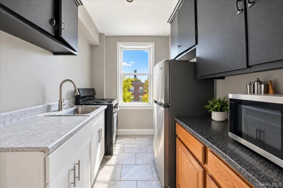 Kitchen featuring white and wood-finish cabinetry, stainless steel sink, black range, and window Kitchen featuring white and wood-finish cabinetry, stainless steel sink, black range, and window