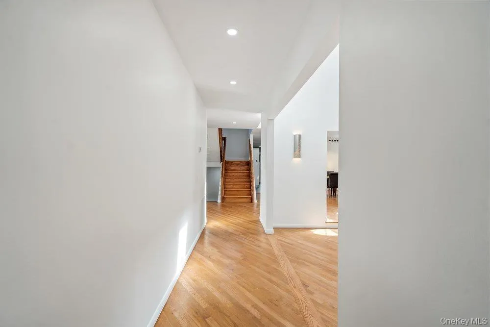 Hardwood flooring, recessed lighting, and a modern wall sconce illuminate the corridor Hardwood flooring, recessed lighting, and a modern wall sconce illuminate the corridor