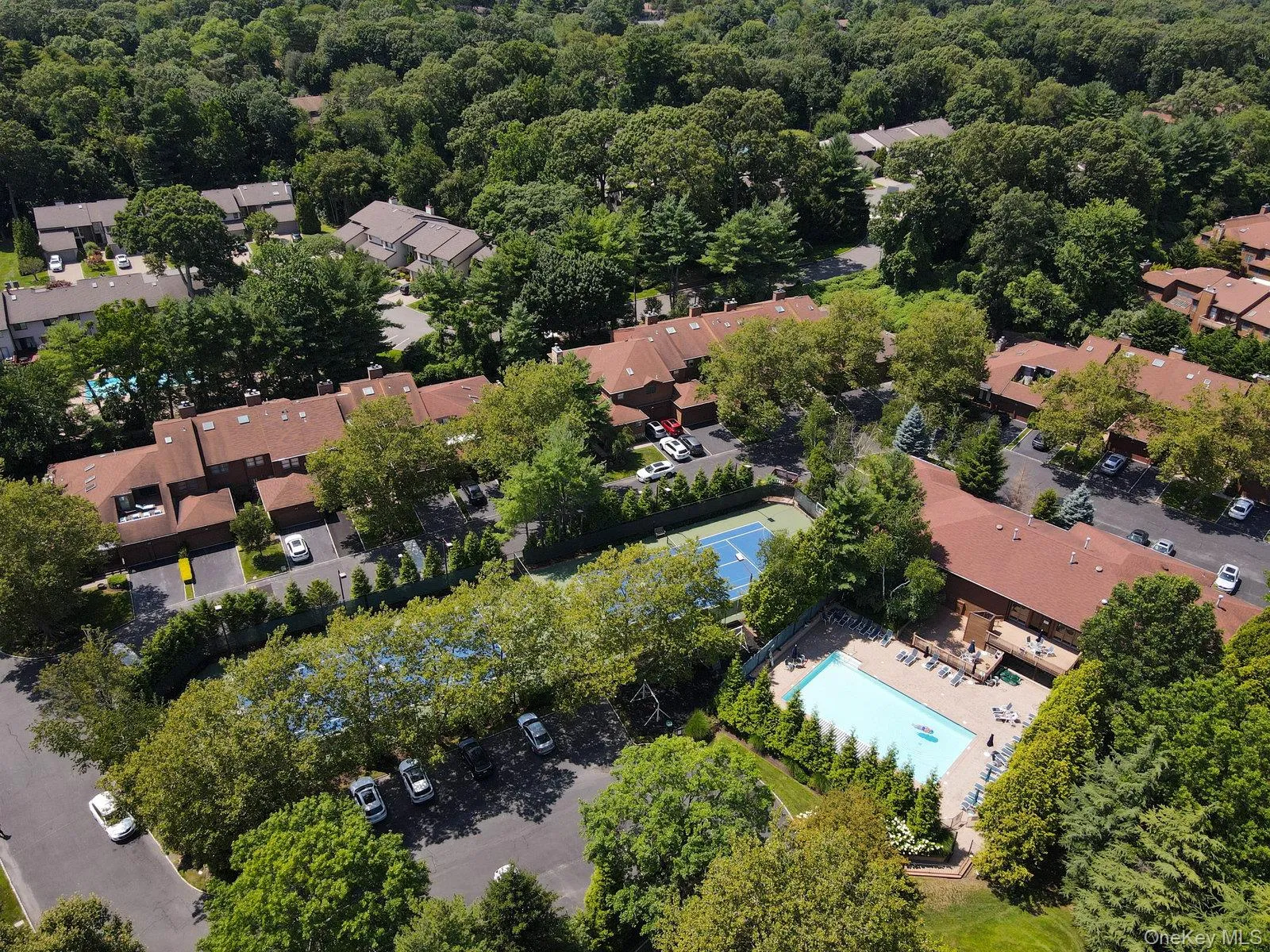 Community featuring multiple residential structures, mature trees, a tennis court, and an outdoor swimming pool with a surrounding deck Community featuring multiple residential structures, mature trees, a tennis court, and an outdoor swimming pool with a surrounding deck