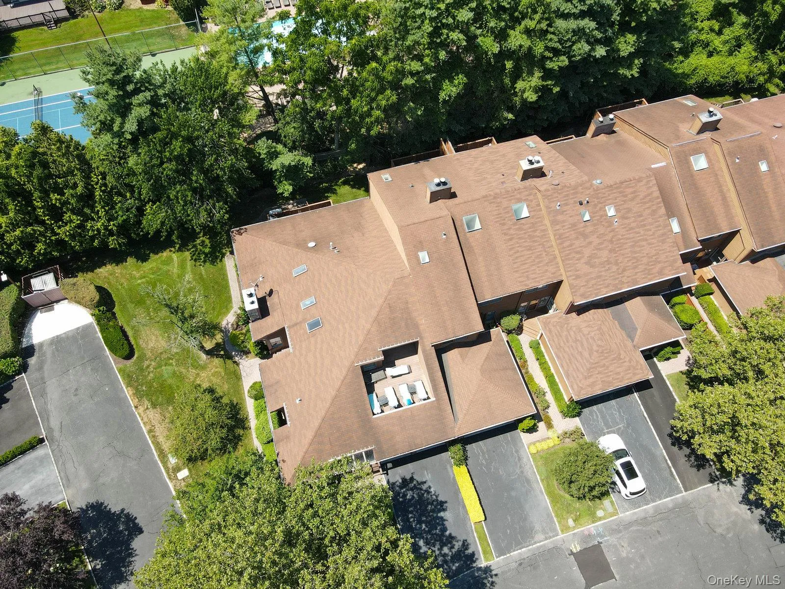 Townhome exterior with a private rooftop patio, multiple skylights, dedicated parking, and surrounding mature trees Townhome exterior with a private rooftop patio, multiple skylights, dedicated parking, and surrounding mature trees