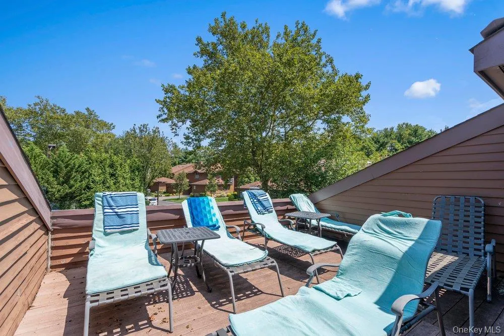 Expansive outdoor deck with wood-finish flooring and sloped shingle siding Expansive outdoor deck with wood-finish flooring and sloped shingle siding