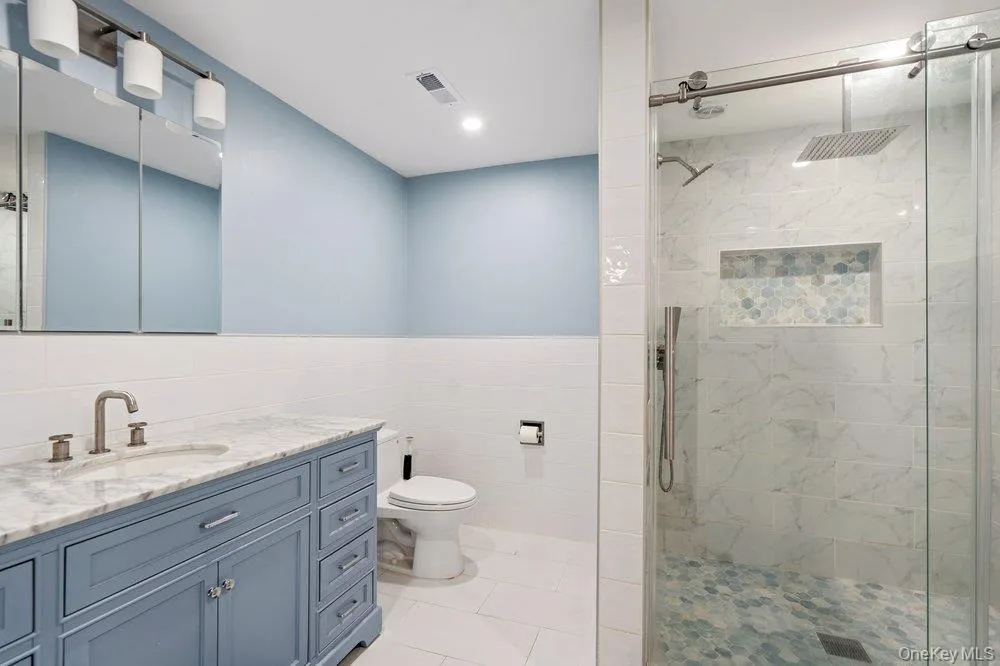 Walk-in shower with a glass enclosure, rain showerhead, and a tiled niche Walk-in shower with a glass enclosure, rain showerhead, and a tiled niche