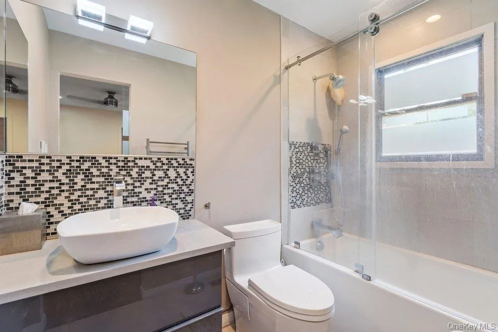 Modern vanity with vessel sink, mosaic tile backsplash, and full glass shower enclosure Modern vanity with vessel sink, mosaic tile backsplash, and full glass shower enclosure