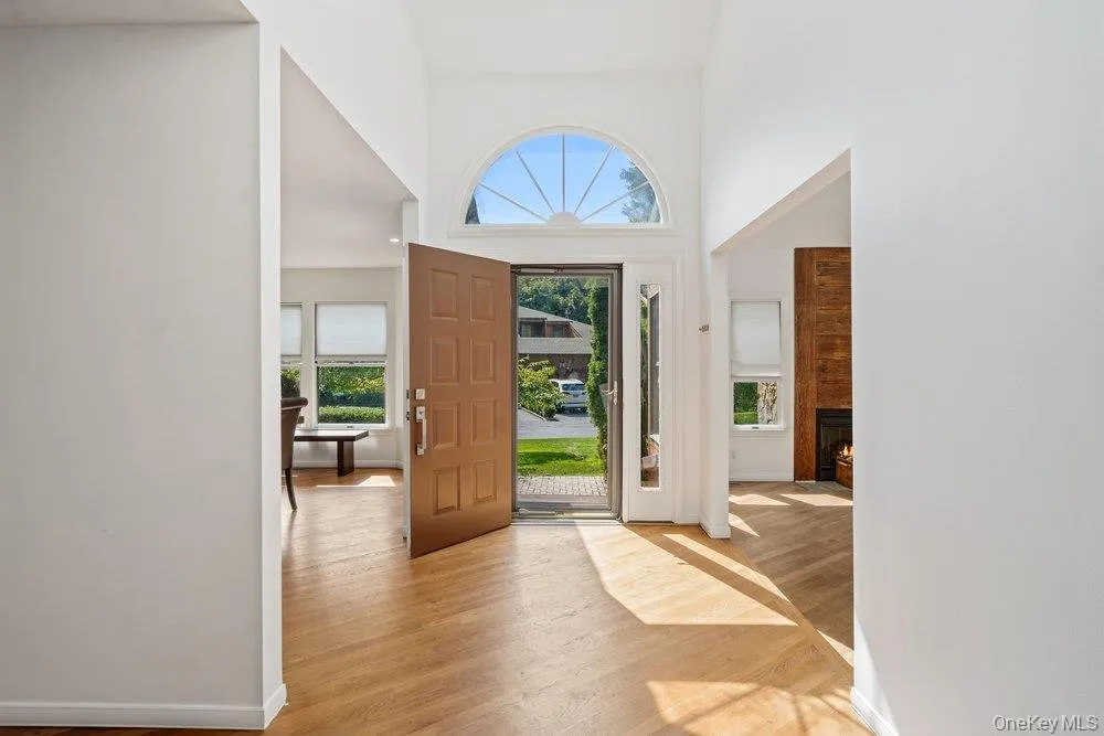 Foyer featuring a paneled entry door, transom window, and wood-finish flooring Foyer featuring a paneled entry door, transom window, and wood-finish flooring