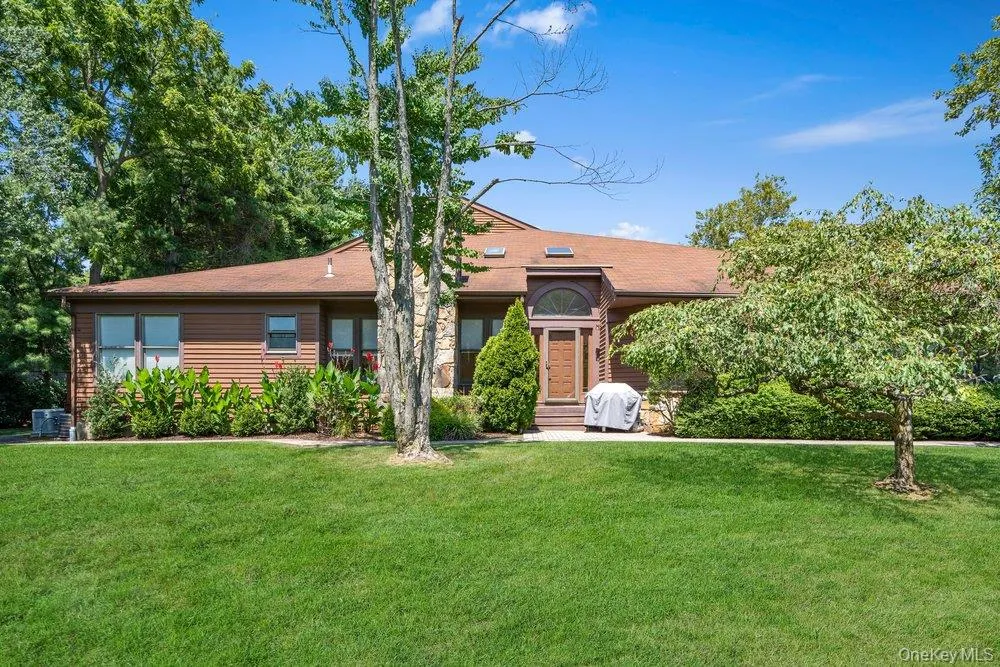 Brown siding exterior with a shingled roof, stone facade accents, and a front entry with an arched transom window Brown siding exterior with a shingled roof, stone facade accents, and a front entry with an arched transom window