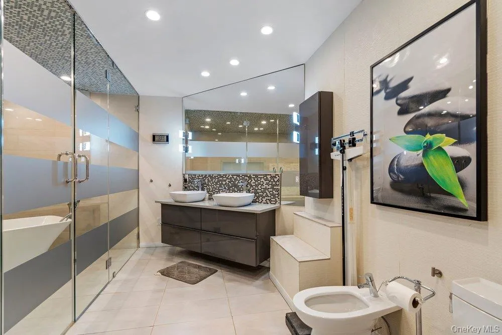 Dual vessel sinks set on a floating vanity with a large wall-mounted mirror Dual vessel sinks set on a floating vanity with a large wall-mounted mirror